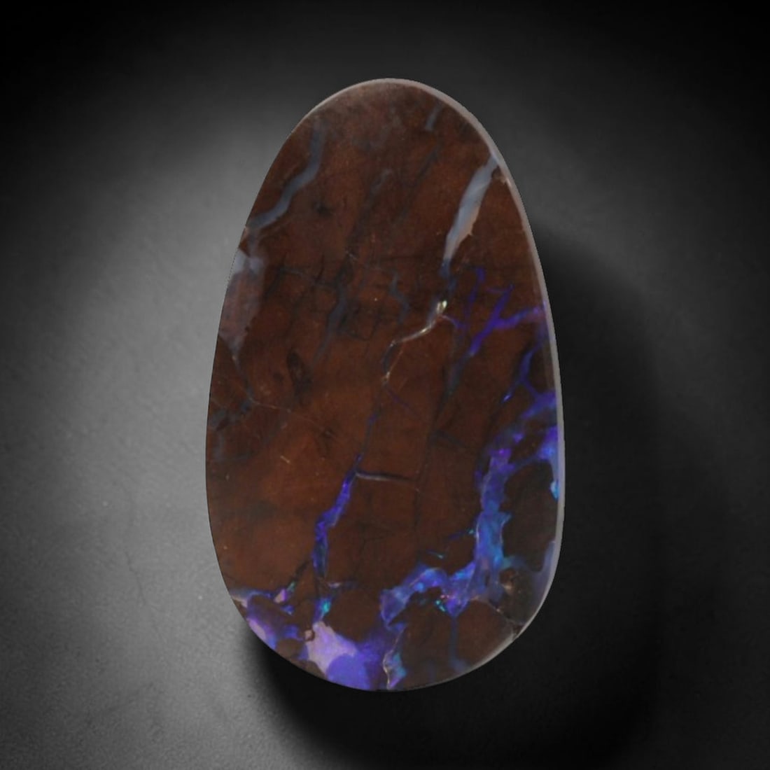 4.93 Carats Matrix Boulder Opal Teardrop Cabochon - Natural Australian Stone, 10XC: This captivating matrix boulder opal cabochon, measuring 16.7 x 9.8 x 3.2 mm, is a dramatic display of natural opal artistry. Polished into a sleek teardrop shape, the stone features a rich, chocolate