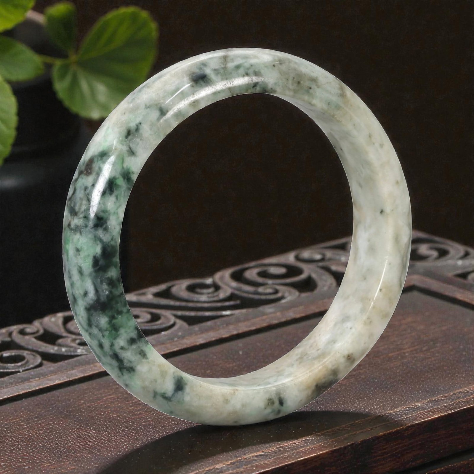 Natural Burmese Type A Jadeite Jade Bangle Bracelet, 20th Century, 84ZK: Carved from jadeite jade with a pale off-white base and irregular dark green mottled inclusions, the bangle is shaped as a solid, continuous circular band with a classic rounded cross-section. The sur