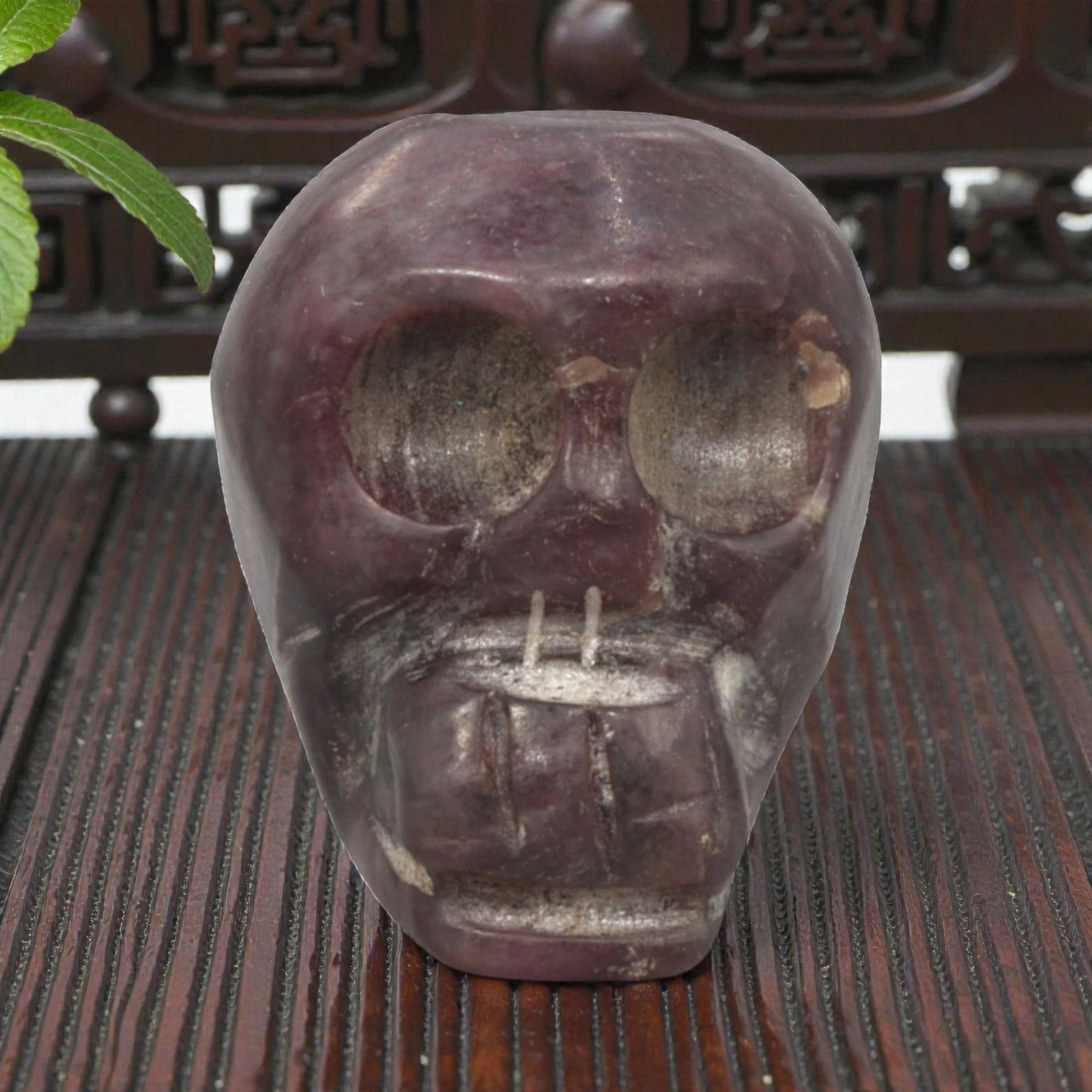 Antique Tibetan Purple Stone Skull Bead, 1AD: Carved from natural purple stone with a rich variegated hue and crystalline texture, the bead is shaped as a stylized human skull. The front face features large, hollowed eye sockets, a simplified nas