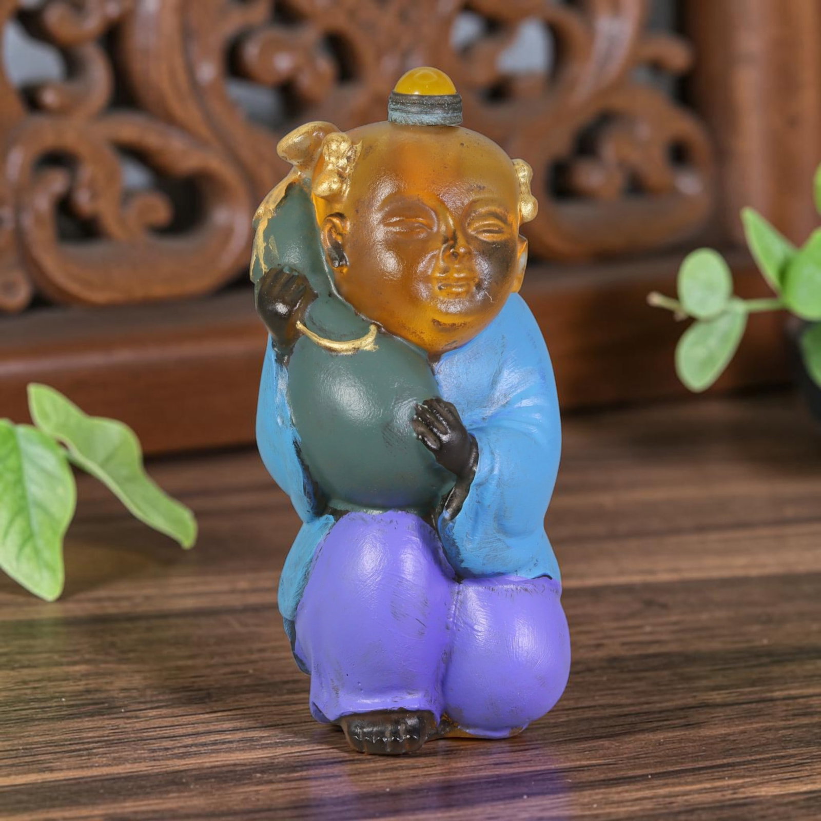 Vintage Chinese Liuli Glass Snuff Bottle - Boy Holding Gourd, 37AS: This snuff bottle is moulded from translucent amber liuli glass, shaped as a young boy cradling a green gilded gourd, a classic symbol of longevity and good fortune. His bright blue robe and purple tr