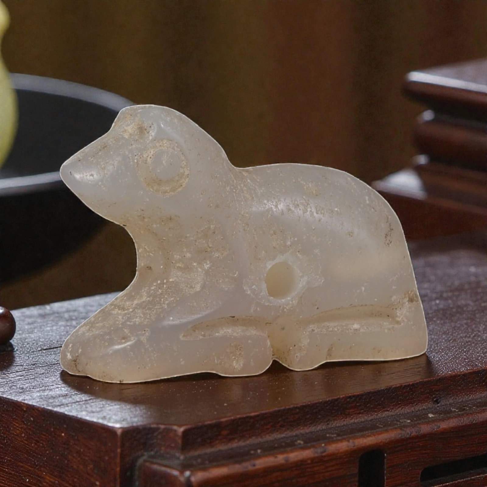 Ancient Bactrian Zoomorphic Chalcedony Amulet, Circa 3rd-2nd Millennium BCE, 83YD: This ancient zoomorphic amulet is carved from translucent pale chalcedony, depicting a stylized recumbent quadruped figure, likely a canine or feline, in profile. The form features simplified anatomic