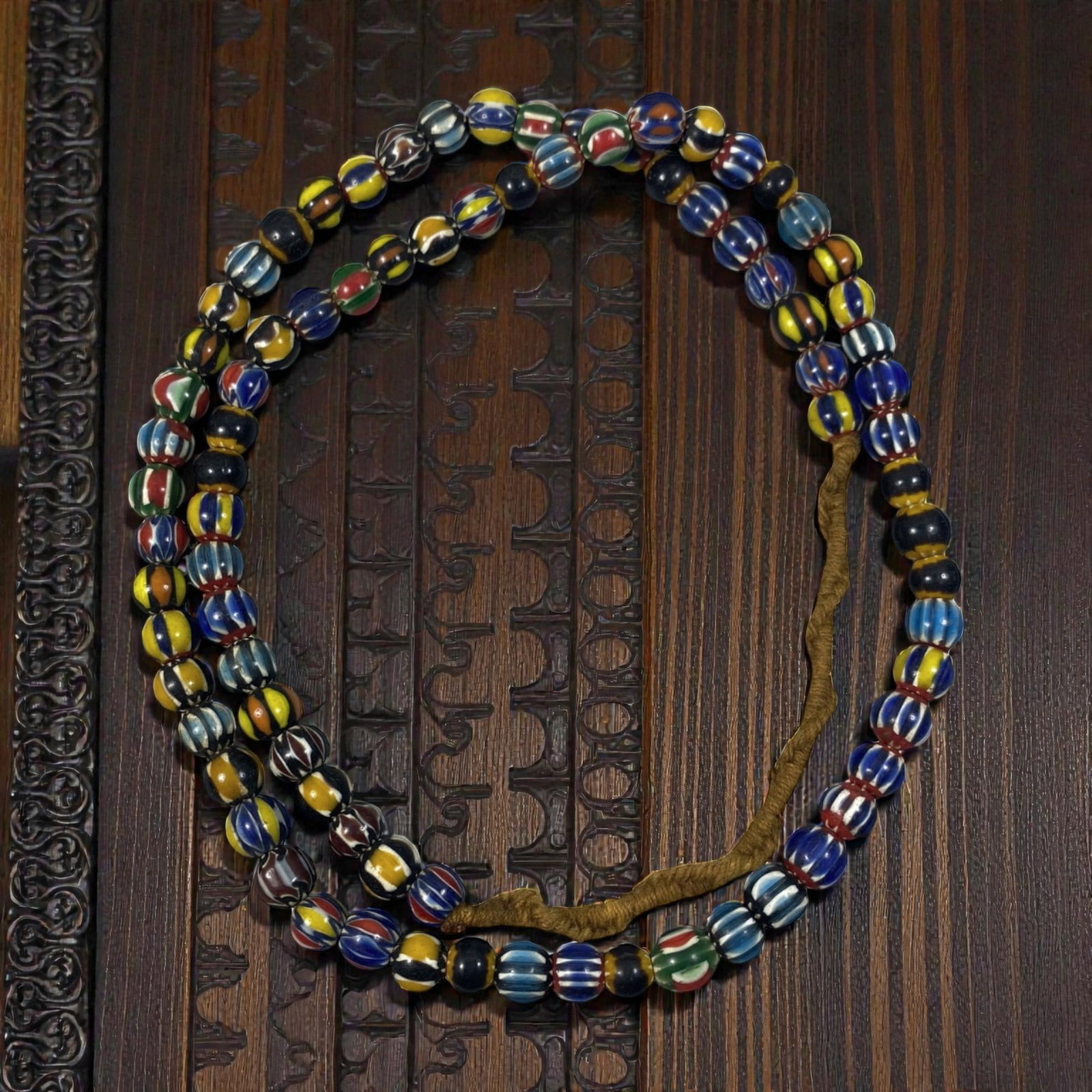 Strand of Antique Chevron Glass Beads, Unstrung, 52AH: A single strand of unstrung antique chevron glass beads, measuring approximately 30 cm in length. The strand features round beads adorned with vibrant, multicolored striped chevron patterns, character