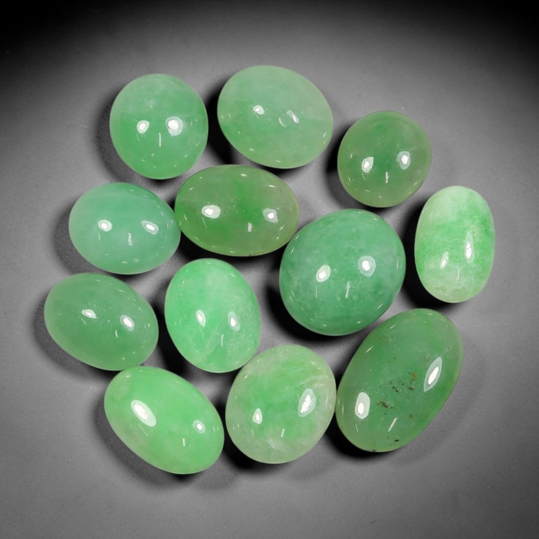 Lot of 12pcs 83.6ct Natural Burmese Type A Apple Green Jadeite Jade Oval Cabochons, 67AV: This wholesale bulk set includes 12 fully untreated natural Burmese Type A jadeite jade oval cabochons with a total combined weight of 83.6ct, consistent sizing of 18x11mm. Every stone boasts a smooth