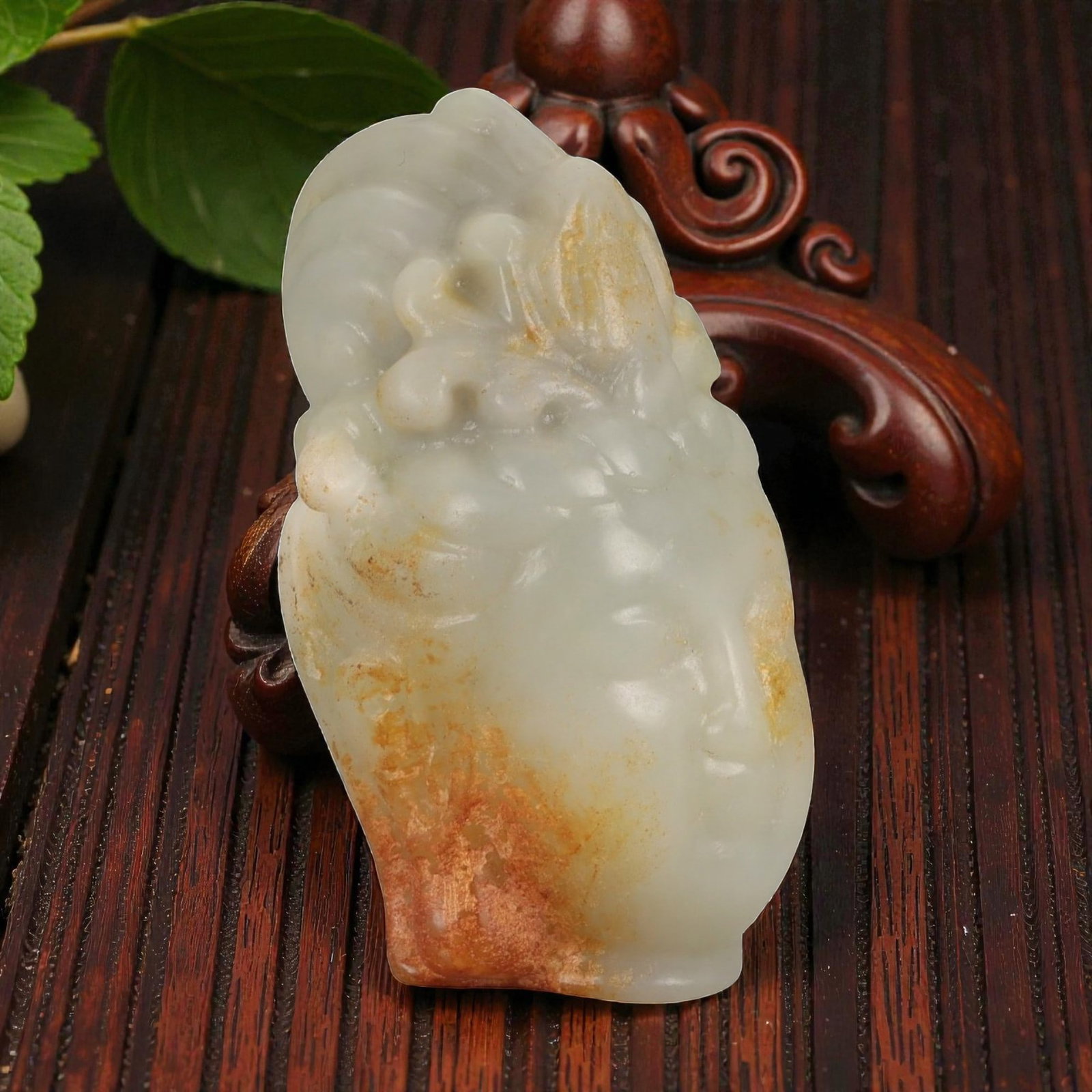 A Chinese Hetian Nephrite Jade Buddha Head, 20th Century, 51FD: Carved from pale celadon Hetian nephrite jade with areas of natural translucency and retained russet skin along the sides and rear. The sculpture represents the head of a Buddha, modeled with a rounde