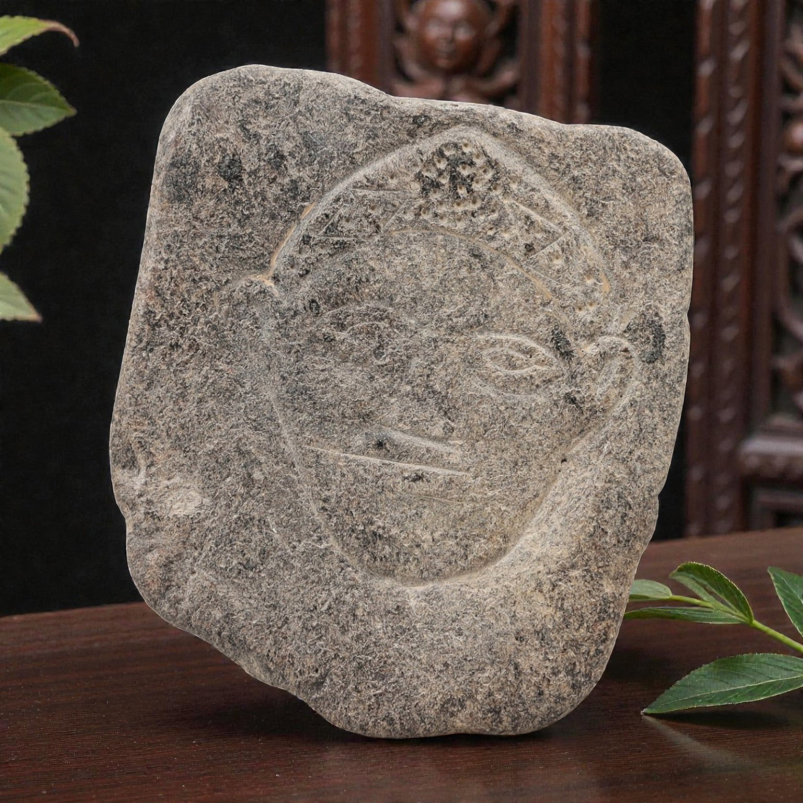 Ancient Sino-Siberian Carved Stone Plaque, 52AG: A carved stone plaque of irregular form, featuring an incised human face with stylized features, including defined eyes, nose, mouth, ears, and a decorated headdress. The stone surface is weathered wi