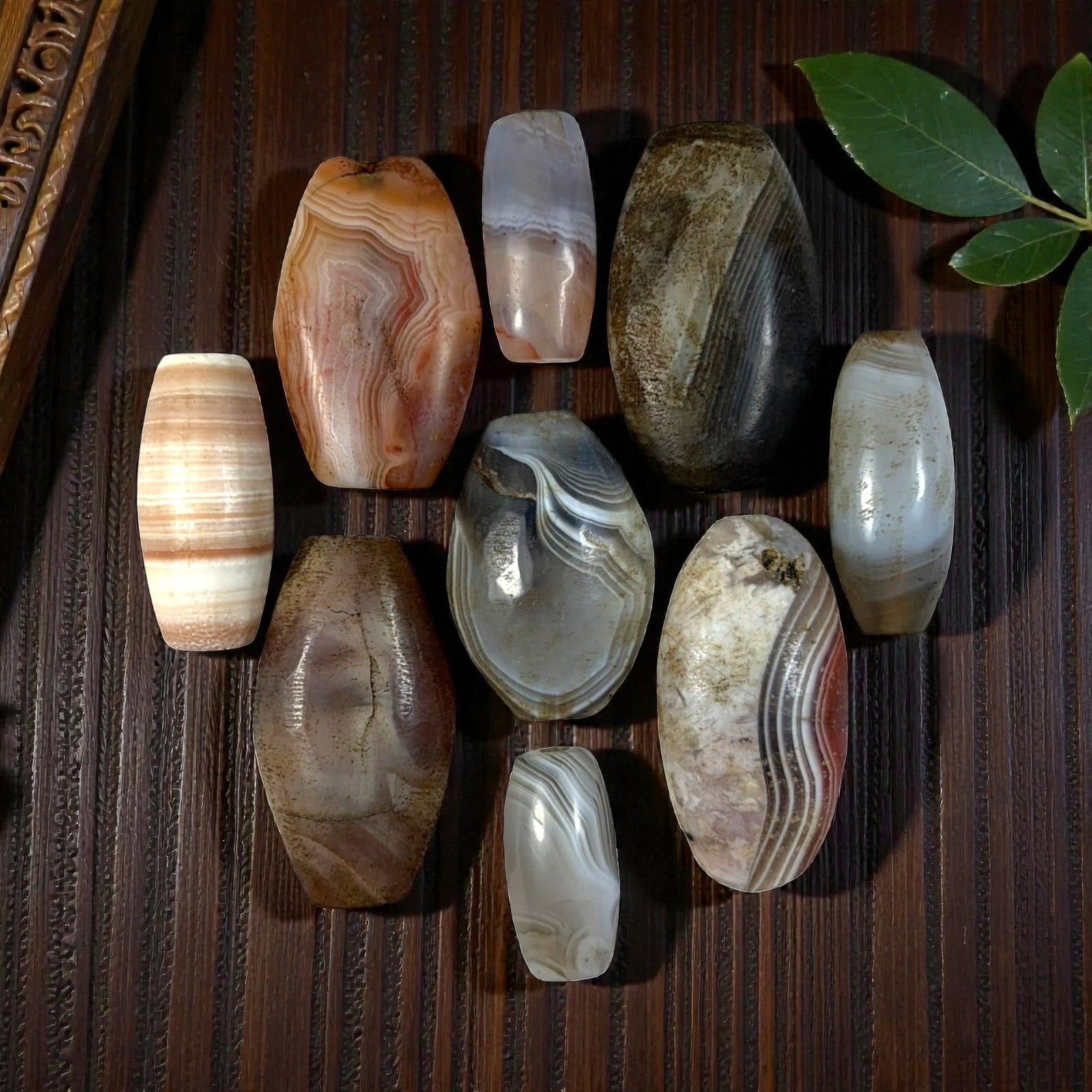 A Lot of 9 Himalayan Banded Agate Beads, Ancient to Antique Period, 26YD: Comprising lot of barrel and ovoid beads, each carved from banded agate with natural tonal variations, many displaying characteristic concentric, linear, and dendritic patterns. The surfaces exhibit s
