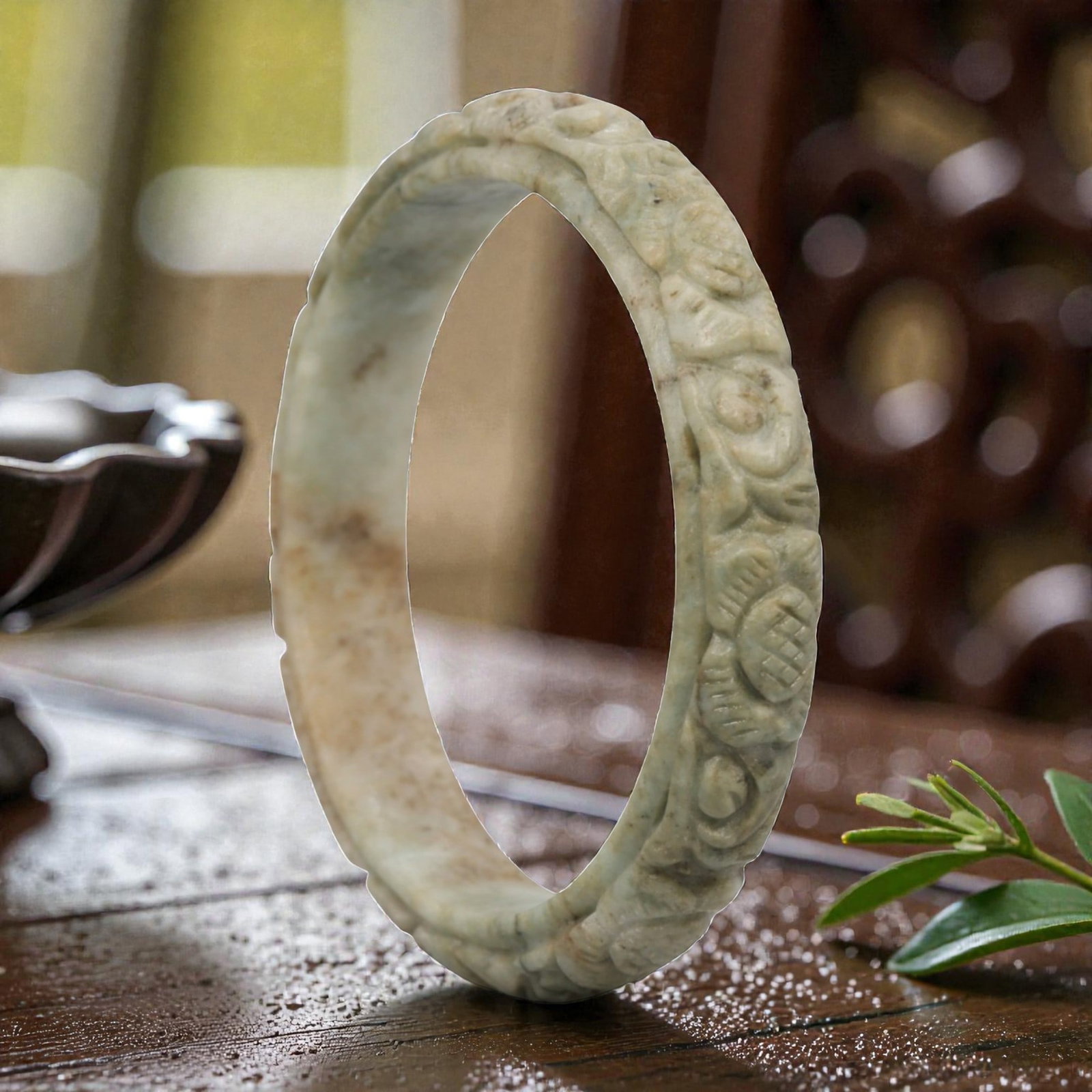 Natural Burmese Type A Carved Jadeite Jade Bangle Bracelet, 20th Century, 23ZL: A fine jadeite bangle of flattened circular form, masterfully carved in relief with a continuous band of floral blossoms and scrolling foliate motifs. The stone exhibits a pale milky-green base, accen