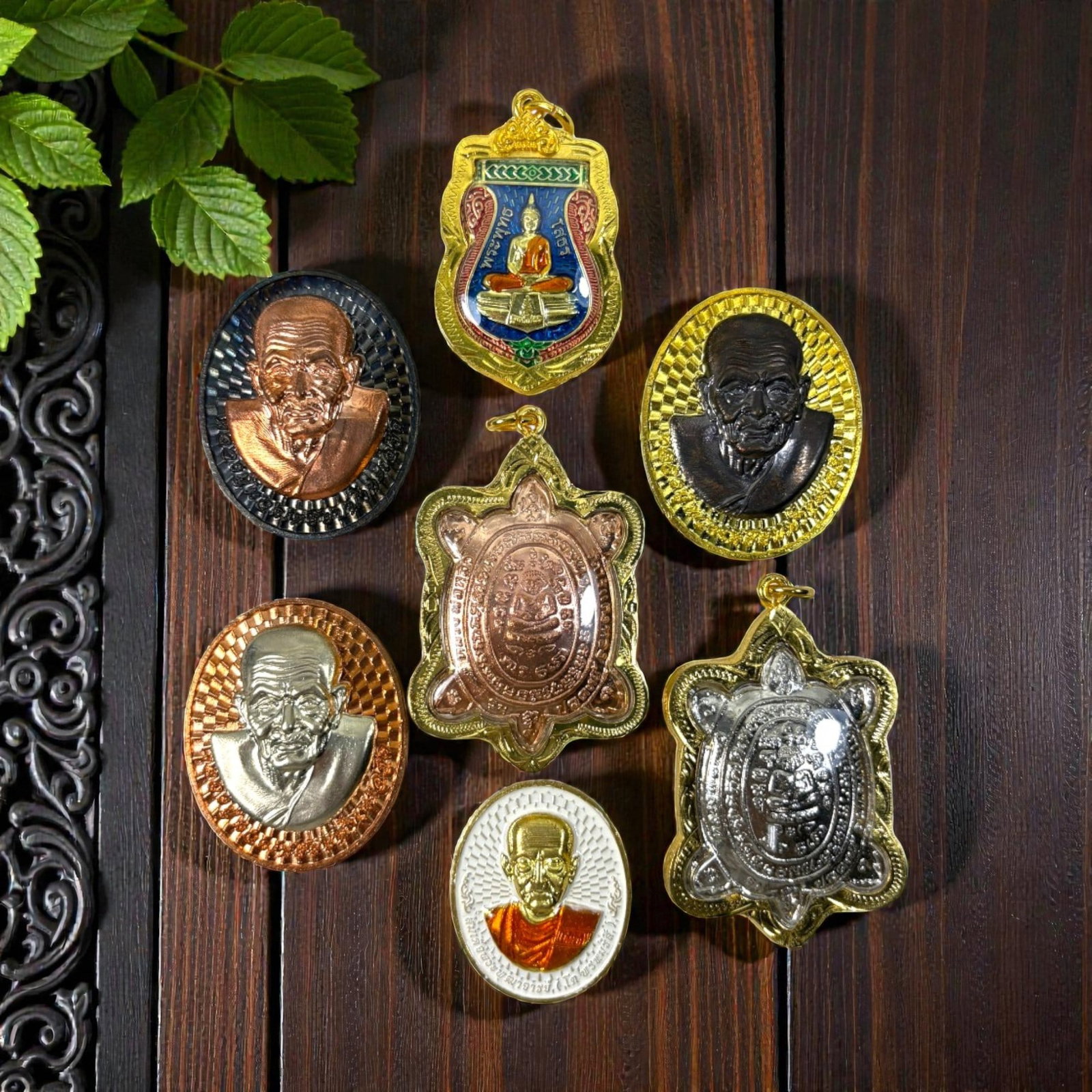 A Lot of 7 Vintage Gilt Thai Buddhist Amulets with Enamel Accents, 22AA: Comprising seven pendants of varying shapes and sizes, ranging from 3.5 to 6 cm in height. Each amulet is encased in ornate gilt metal frames, some accented with colorful enamelwork. The group include