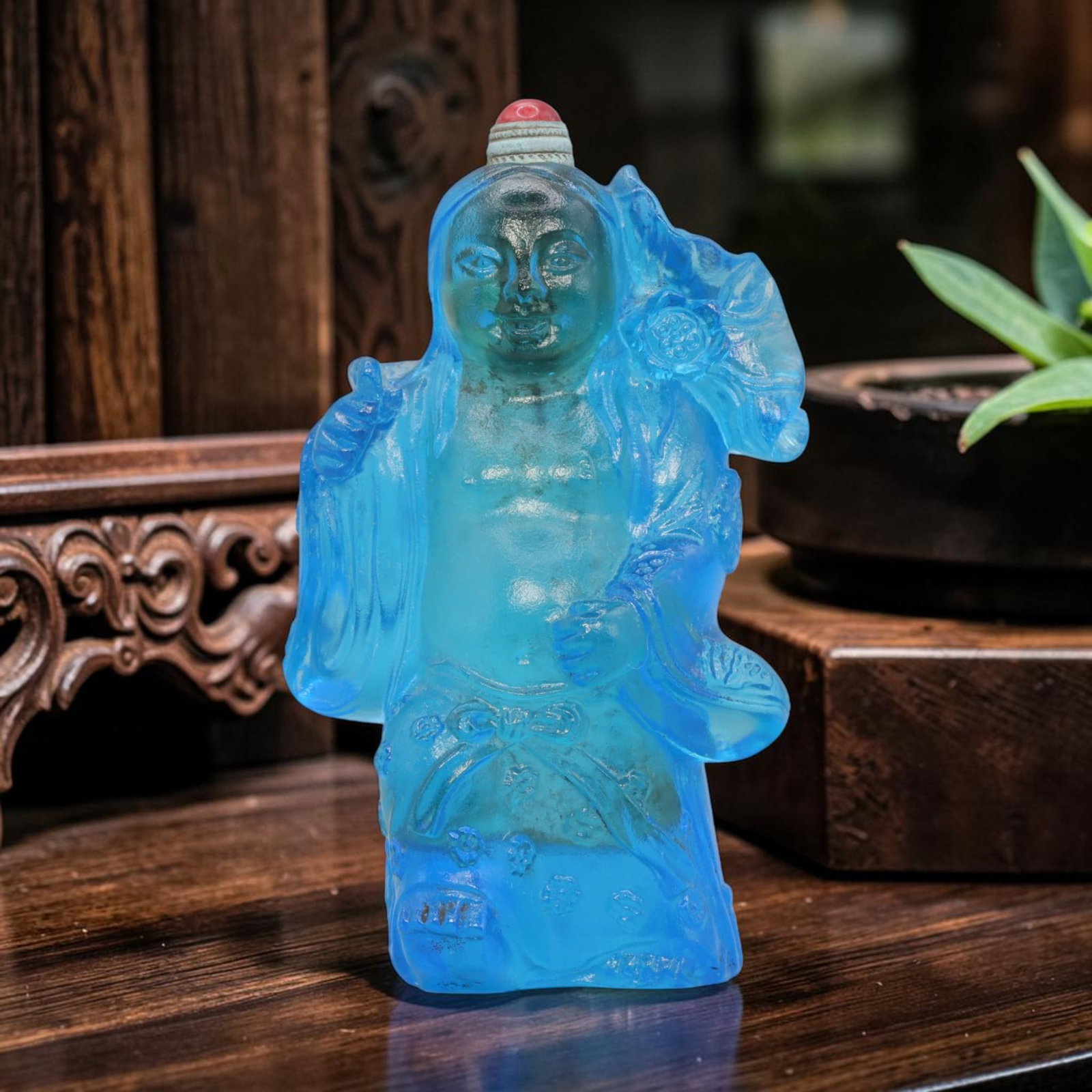 Vintage Chinese Blue Liuli Snuff Bottle - Figure, 60YF: Crafted from translucent sky-blue liuli glass, this snuff bottle is formed as a standing figure, depicted with a rounded belly and smiling face, draped in flowing robes adorned with floral and knot mo