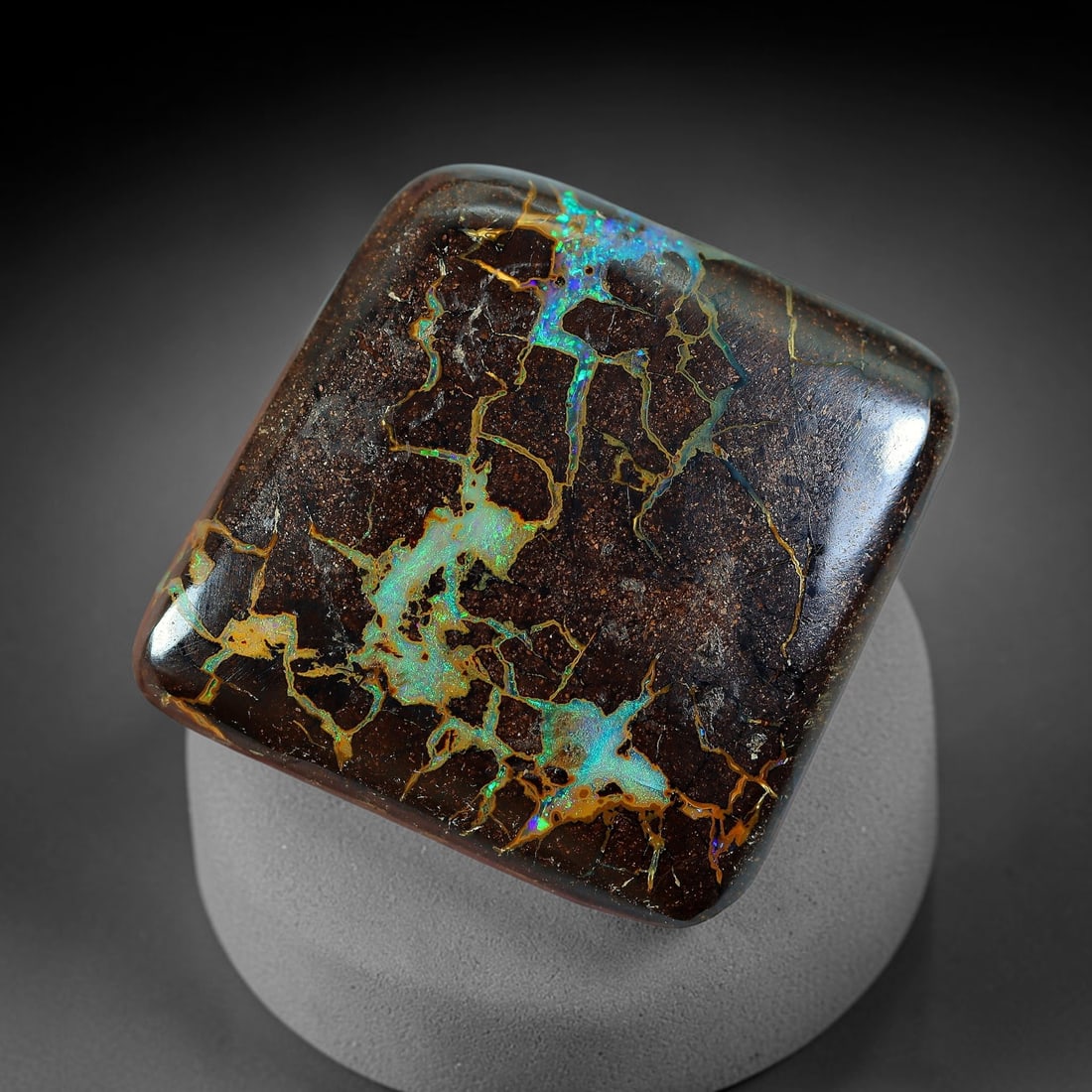 25.55ct Natural Australian Queensland Matrix Boulder Opal Cabochon, 17AV: Hand polished large rounded square cushion cabochon of natural Queensland matrix boulder opal, featuring deep dark speckled ironstone matrix threaded with intricate golden veining interspersed with lu