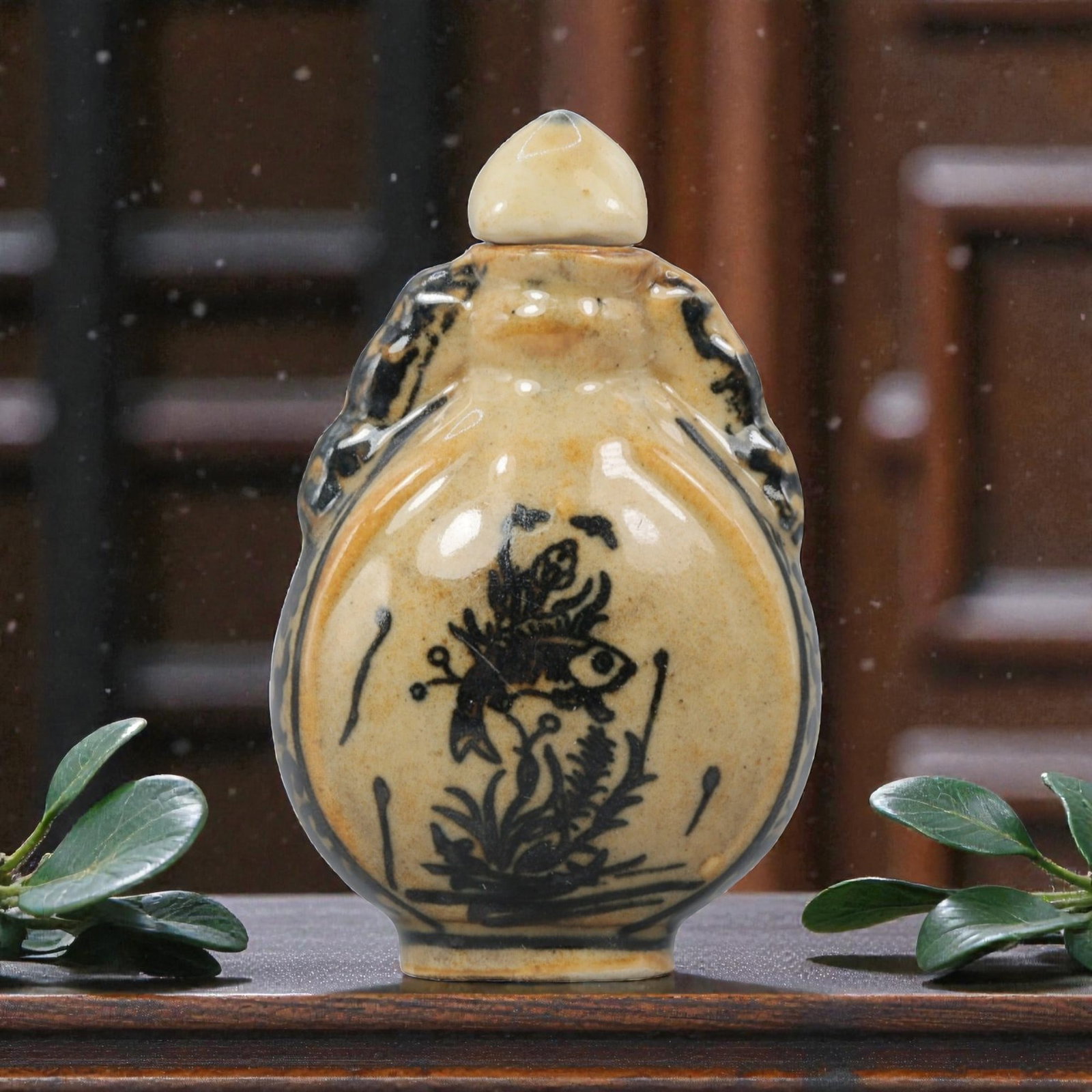 A Chinese Porcelain Moon Flask Snuff Bottle, 20th Century, 61BE: Crafted from porcelain with a pale cream glaze and decorated in underglaze black, the snuff bottle is formed in a flattened moon flask (bianhu) shape, with molded beast-head handles to either side, a 