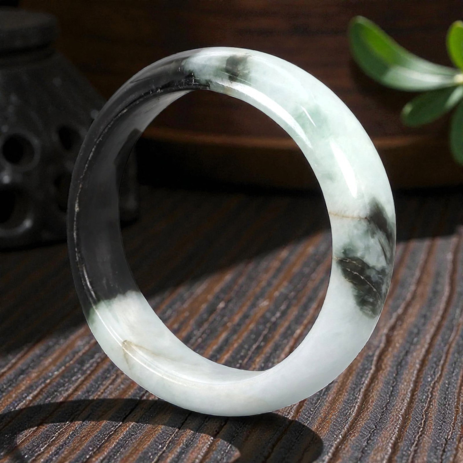 Natural Burmese Type A Jadeite Jade Bangle Bracelet, 20th Century, 99ZK: Carved from jadeite jade with a striking bi-color composition of opaque pale white and translucent deep blackish-green, the bangle is formed as a solid circular band with a flattened rounded cross-sec