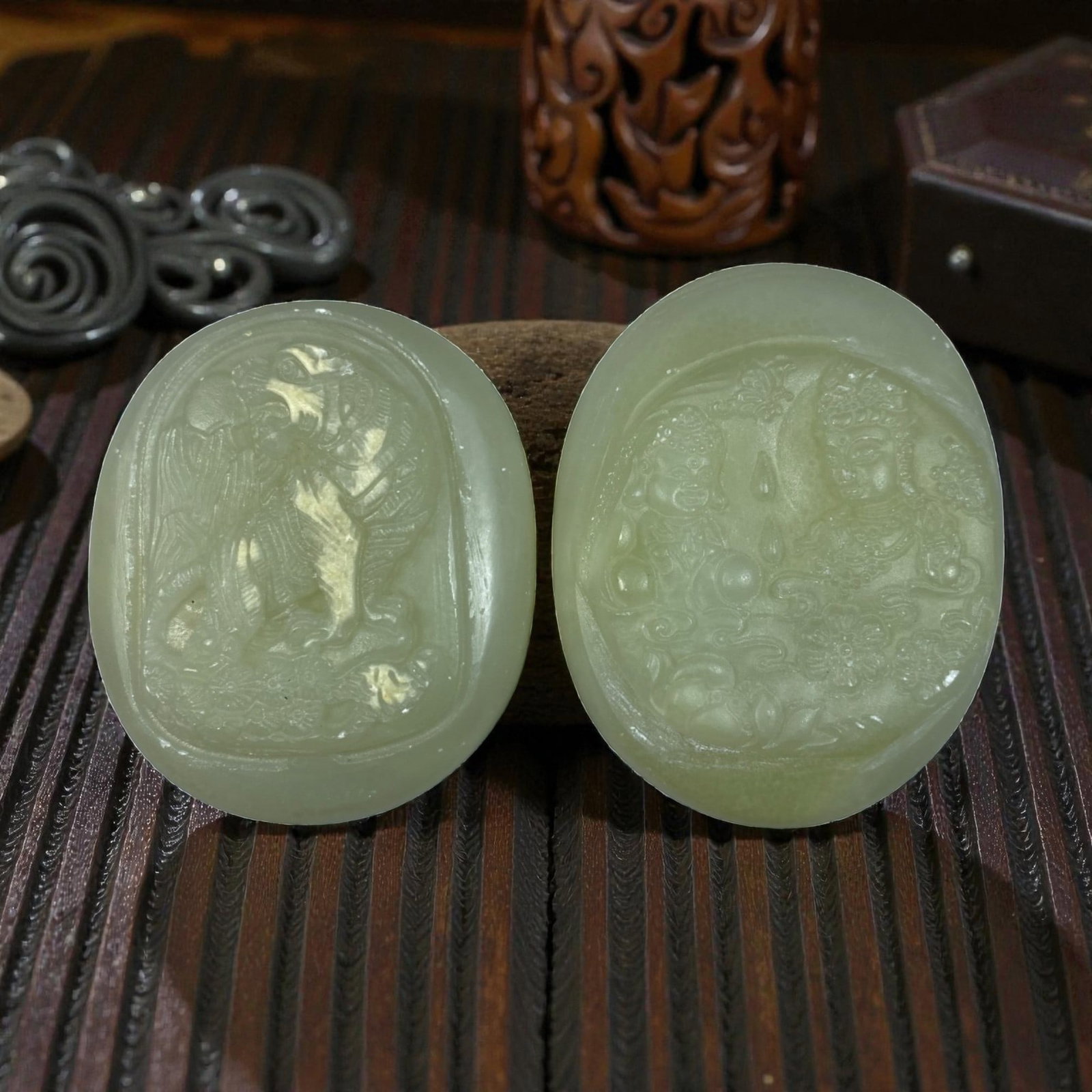 Lot of 2 Chinese Hetian Nephrite Jade Plaques Pendants, 58AG: The lot comprises two oval nephrite jade plaques, both carved from pale celadon stone with a smooth, polished finish. The left plaque features a relief carving of a mythical guardian lion (foo dog) am