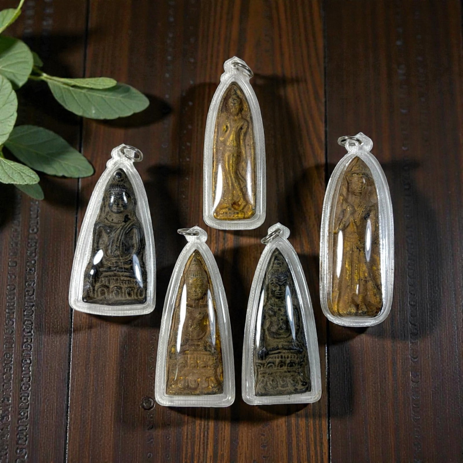 A Lot of 5 Vintage Thai Buddhist Amulets in Clear Cases, 36AA: Comprising five pendants ranging from 7.5 to 9 cm in height. Each amulet features aged devotional imagery, including seated and standing Buddha forms, many with residual gold leaf accents. They are en