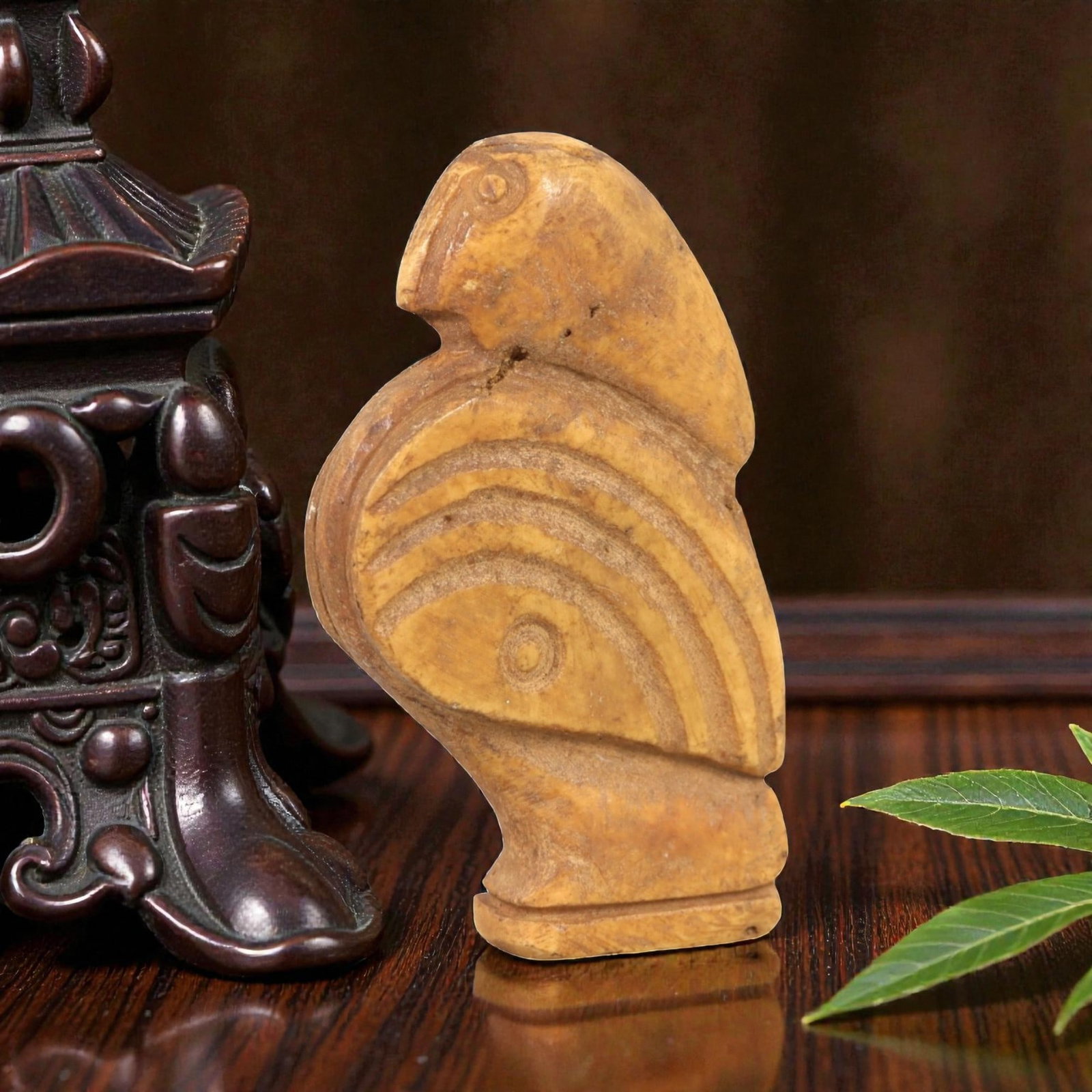 Ancient Bone Bird Amulet - Near Eastern Figurine, 84AL: Carved from tan bone, this amulet depicts a stylized avian form with a rounded head, incised eye, and curved beak. The body features concentric incised linear patterns creating a layered, feather-like