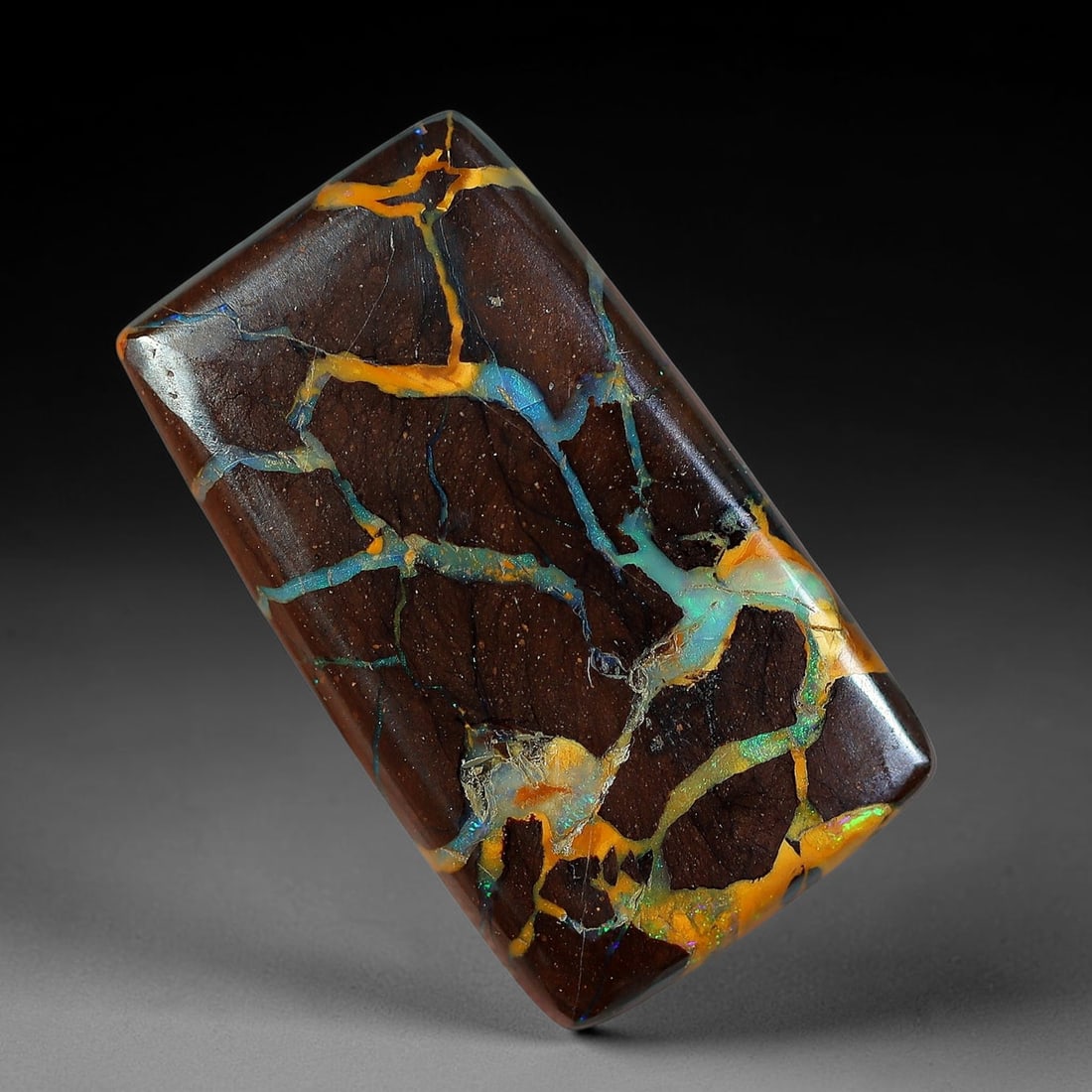 7.66ct Natural Australian Queensland Matrix Boulder Opal Rounded Rectangle Cabochon, 75AV: Hand polished slim rounded rectangular bar cabochon crafted from natural Queensland matrix boulder opal, featuring rich dark speckled brown ironstone matrix threaded with interwoven golden amber and l
