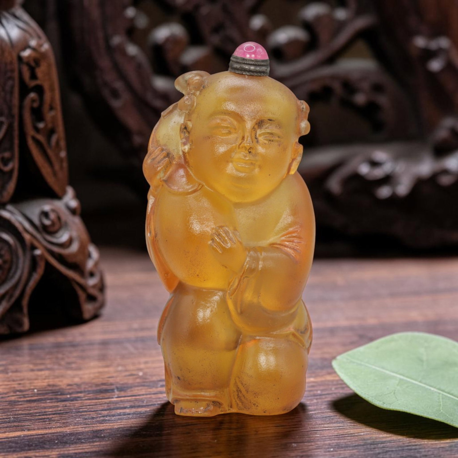 Vintage Chinese Liuli Glass Snuff Bottle - Child Figure, 83YF: Crafted from translucent amber-toned liuli glass, this snuff bottle is shaped as a traditional Chinese child figure, kneeling and holding a large gourd. The carving exhibits rounded, smooth features w