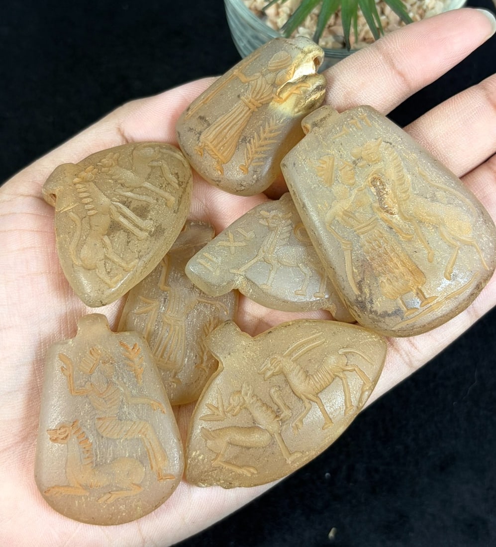 Lot of 7 Ancient Sasanian Rock Crystal Intaglio Amulet Pendants, 45YD: This seven-piece antiquity lot features hand-carved shield-shaped pendants crafted from translucent natural rock crystal, each etched with fine Sasanian intaglio iconography including robed human figu