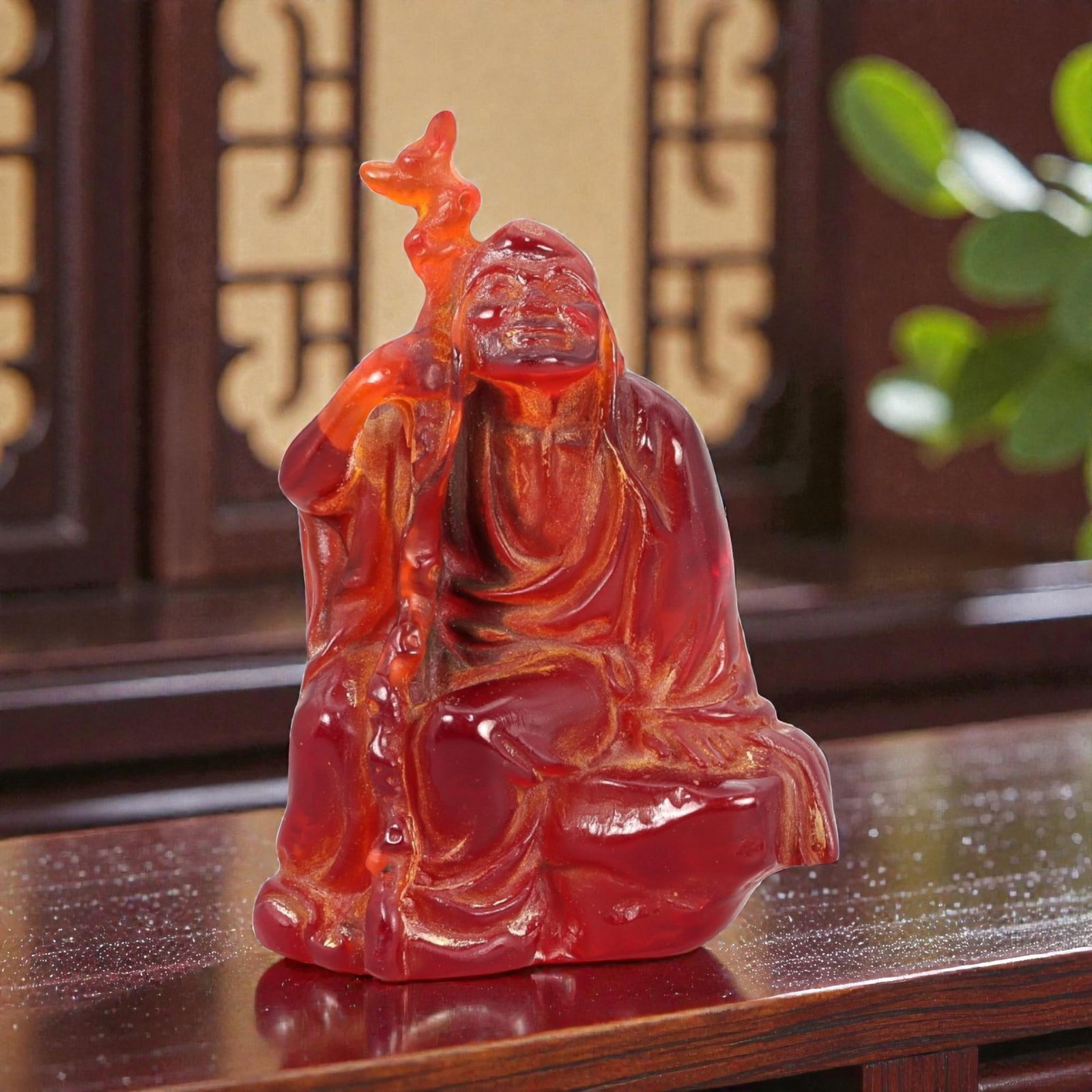 A Chinese Amber-Resin Figure of a Luohan, 20th Century, 44FH: Cast or carved from translucent amber-colored red resin with internal tonal variation, localized inclusions, and minor entrapped bubbles, the figure represents a seated luohan shown resting against a 