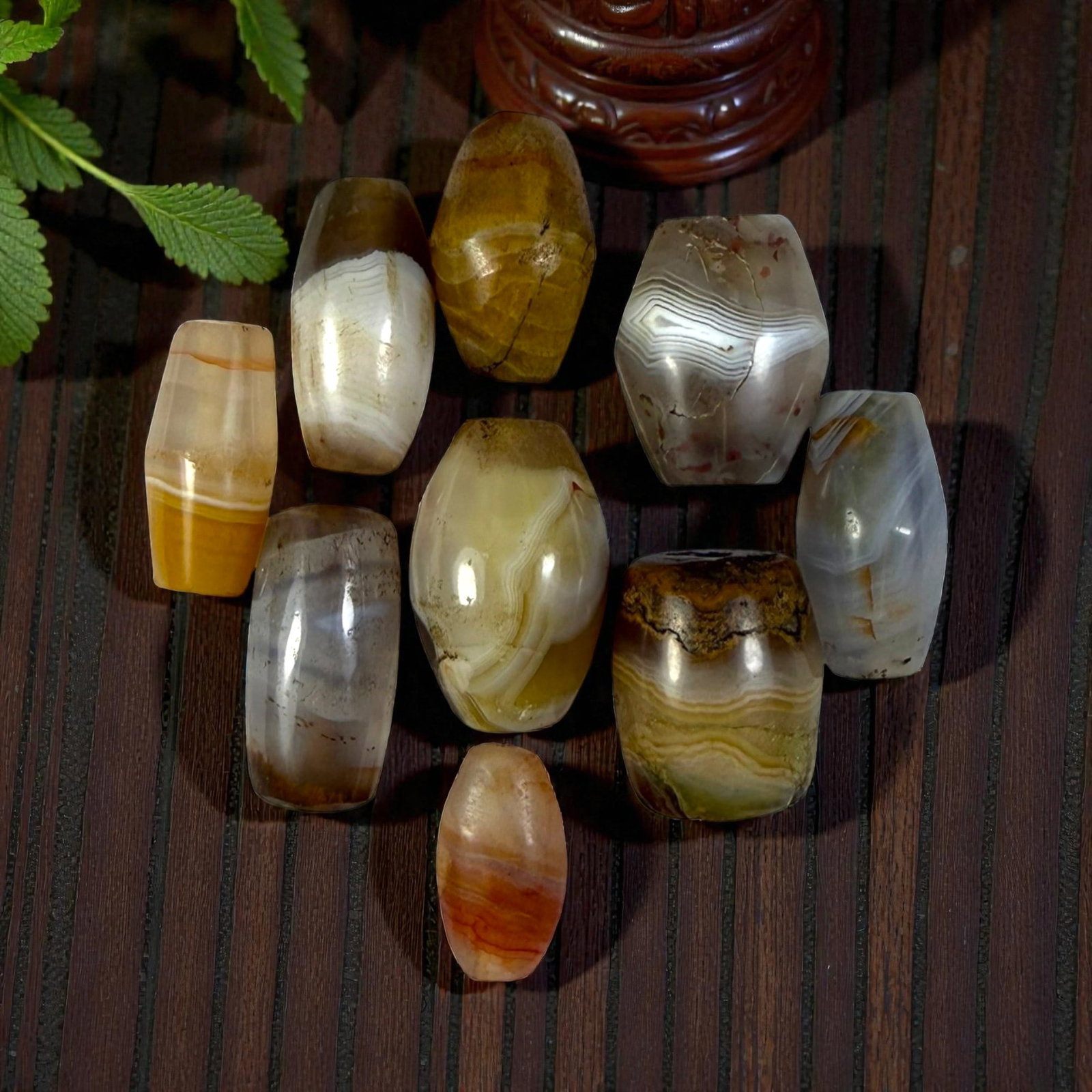 A Lot of 9 Himalayan Banded Agate Beads, Ancient to Antique Period, 16YD: Comprising lot of barrel and ovoid beads, each carved from banded agate with natural tonal variations, many displaying characteristic concentric, linear, and dendritic patterns. The surfaces exhibit s