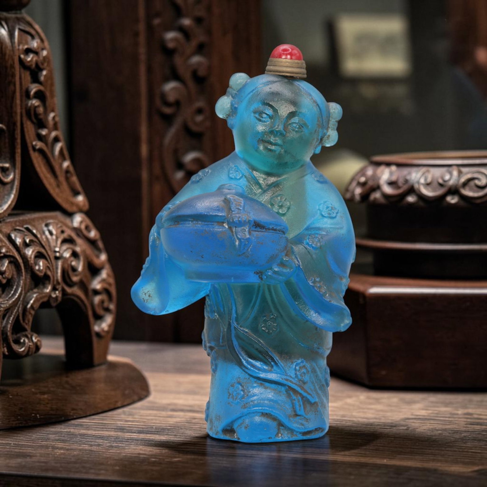 Vintage Chinese Blue Liuli Glass Snuff Bottle - Child Figurine, 69YF: Crafted from translucent blue liuli glass, this vintage Chinese snuff bottle is modelled as a child figure in traditional dress holding a covered vessel. The glass exhibits a rich blue hue with subtle