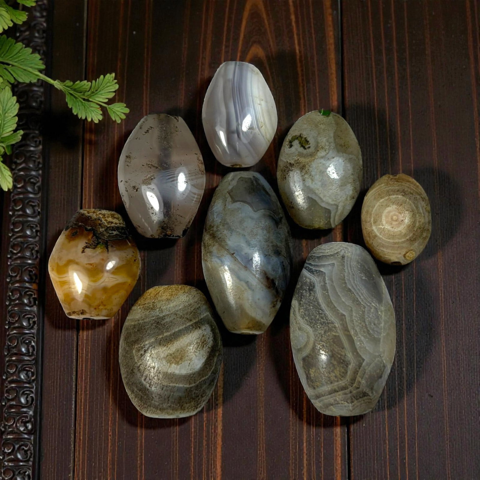 A Lot of 9 Himalayan Banded Agate Beads, Ancient to Antique Period, 39AN: Comprising lot of barrel and ovoid beads, each carved from banded agate with natural tonal variations, many displaying characteristic concentric, linear, and dendritic patterns. The surfaces exhibit s