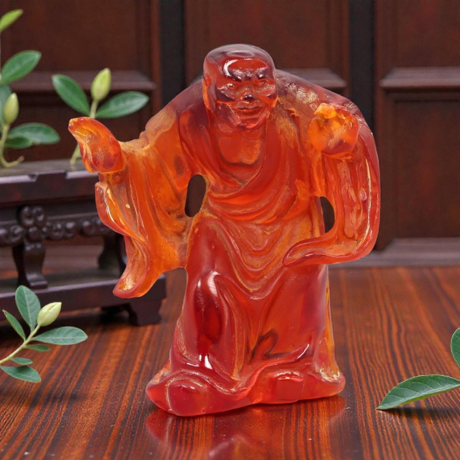 A Chinese Amber-Resin Figure of a Luohan, 20th Century, 42FH: Cast or carved from translucent amber-colored red resin with internal tonal variation, scattered inclusions, and minor entrapped bubbles, the figure represents a standing luohan shown in an animated p