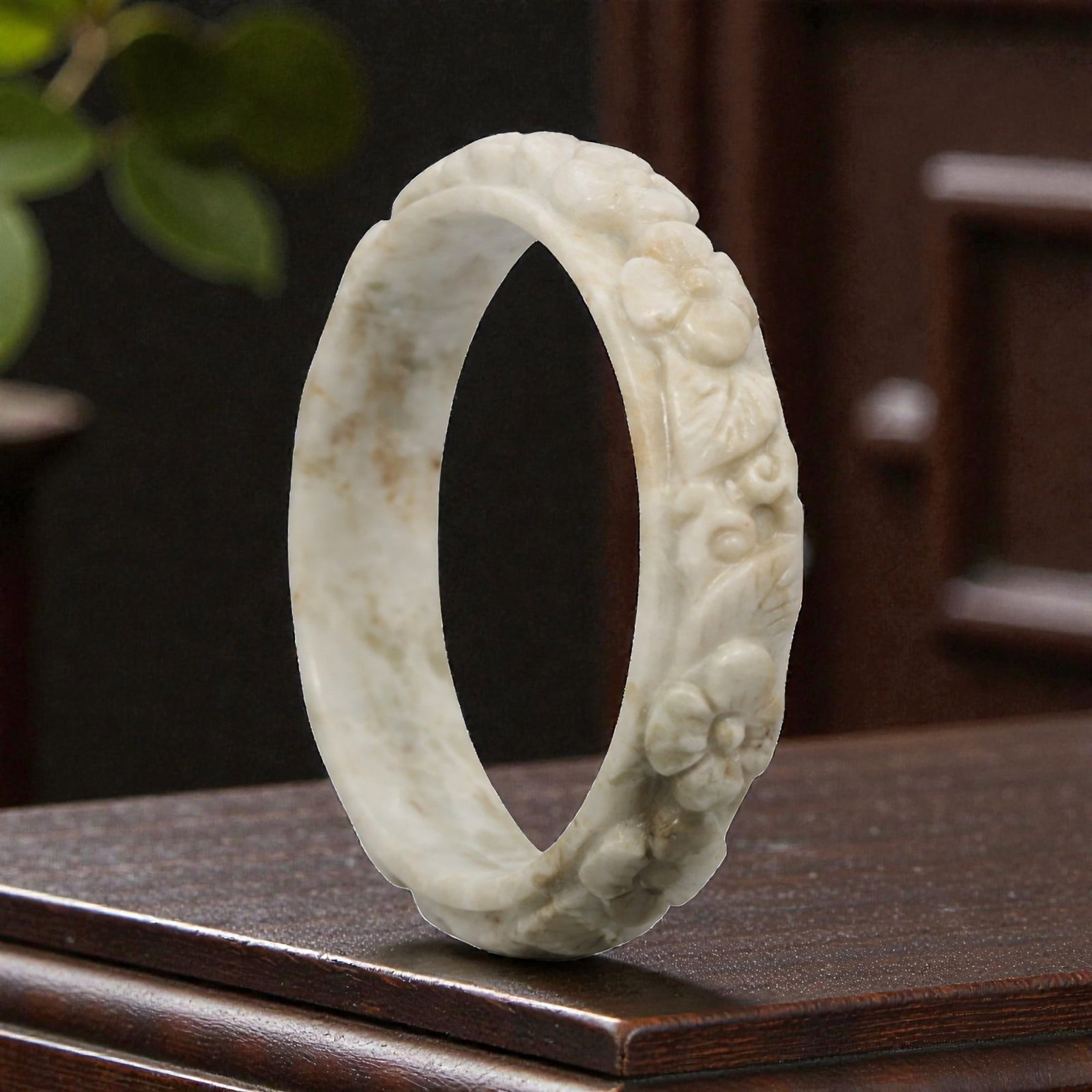 Natural Burmese Type A Carved Jadeite Jade Bangle Bracelet, 20th Century, 29ZL: A fine jadeite bangle of flattened circular form, masterfully carved in relief with a continuous band of floral blossoms and scrolling foliate motifs. The stone exhibits a creamy white base, accented 