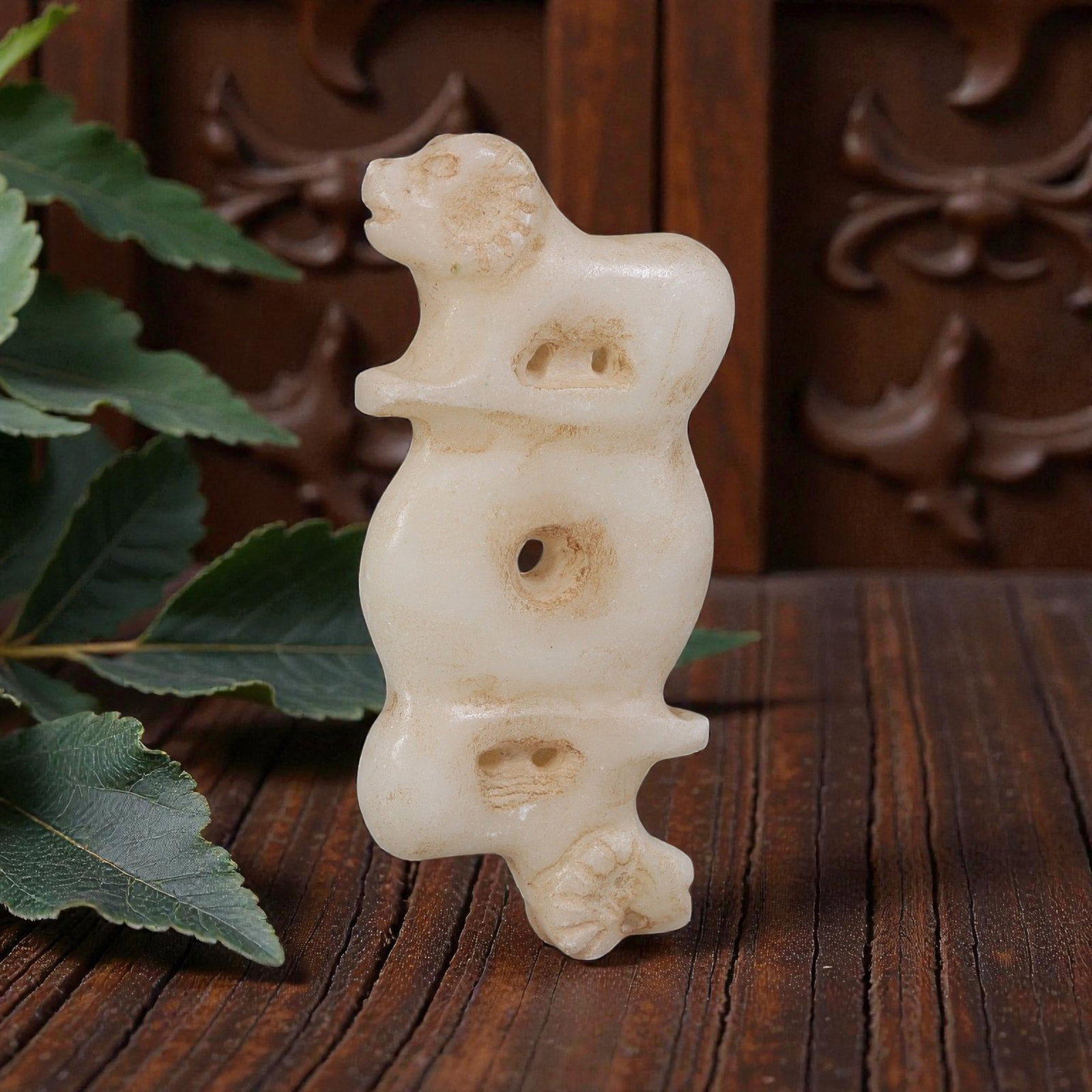 Ancient Near Eastern Marble Ornamental Amulet, Iron Age to Sasanian Period, 68YD: This ancient ornamental amulet is carved from pale white marble, featuring a symmetrical double zoomorphic form with animal heads at both ends, likely representing rams. The central body includes a pe