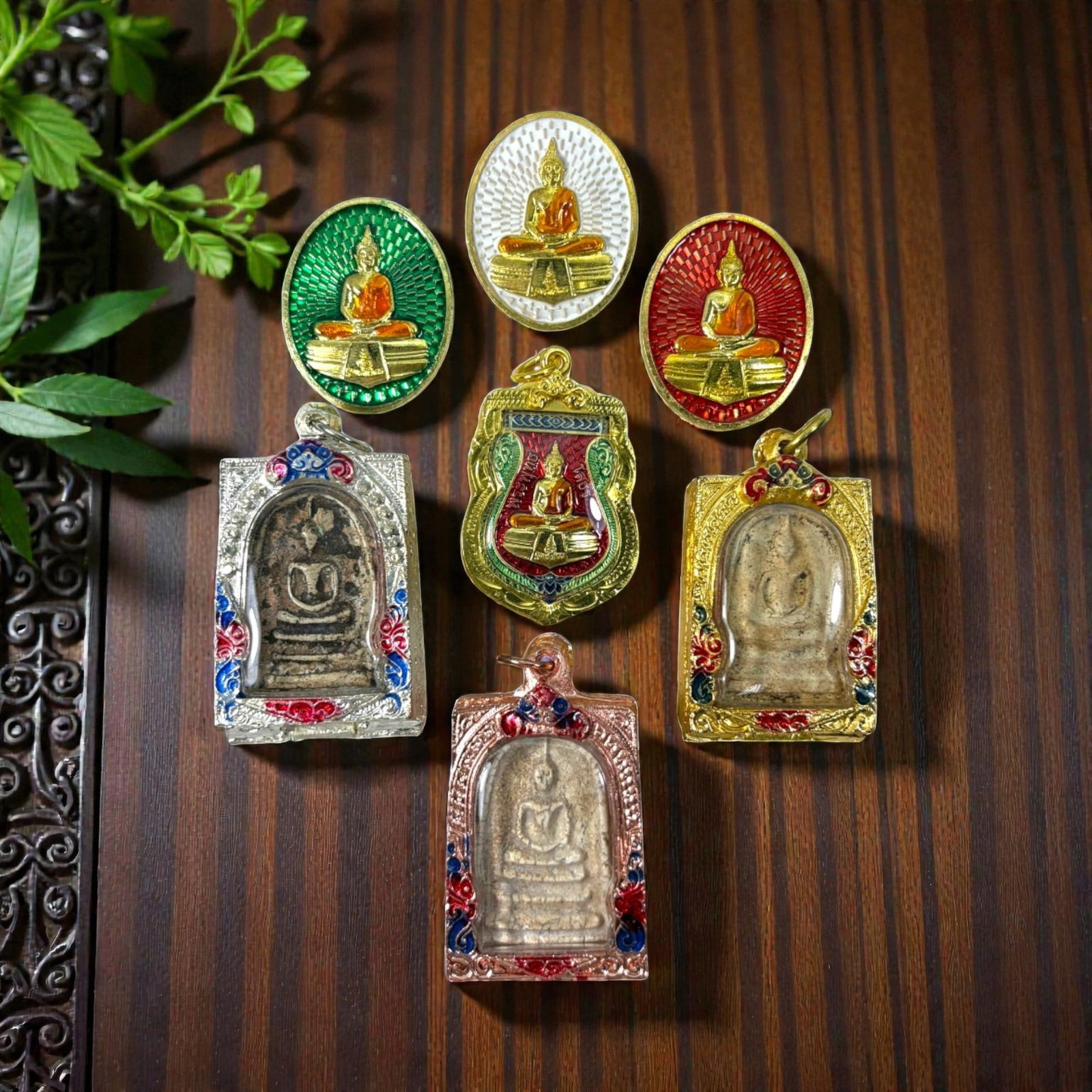 A Lot of 7 Vintage Gilt Thai Buddhist Amulets with Enamel Accents, 24AA: Comprising seven pendants of varying shapes and sizes, ranging from 4 to 5.5 cm in height. The group includes three oval enamel medallions depicting seated Buddha figures, and four rectangular amulets