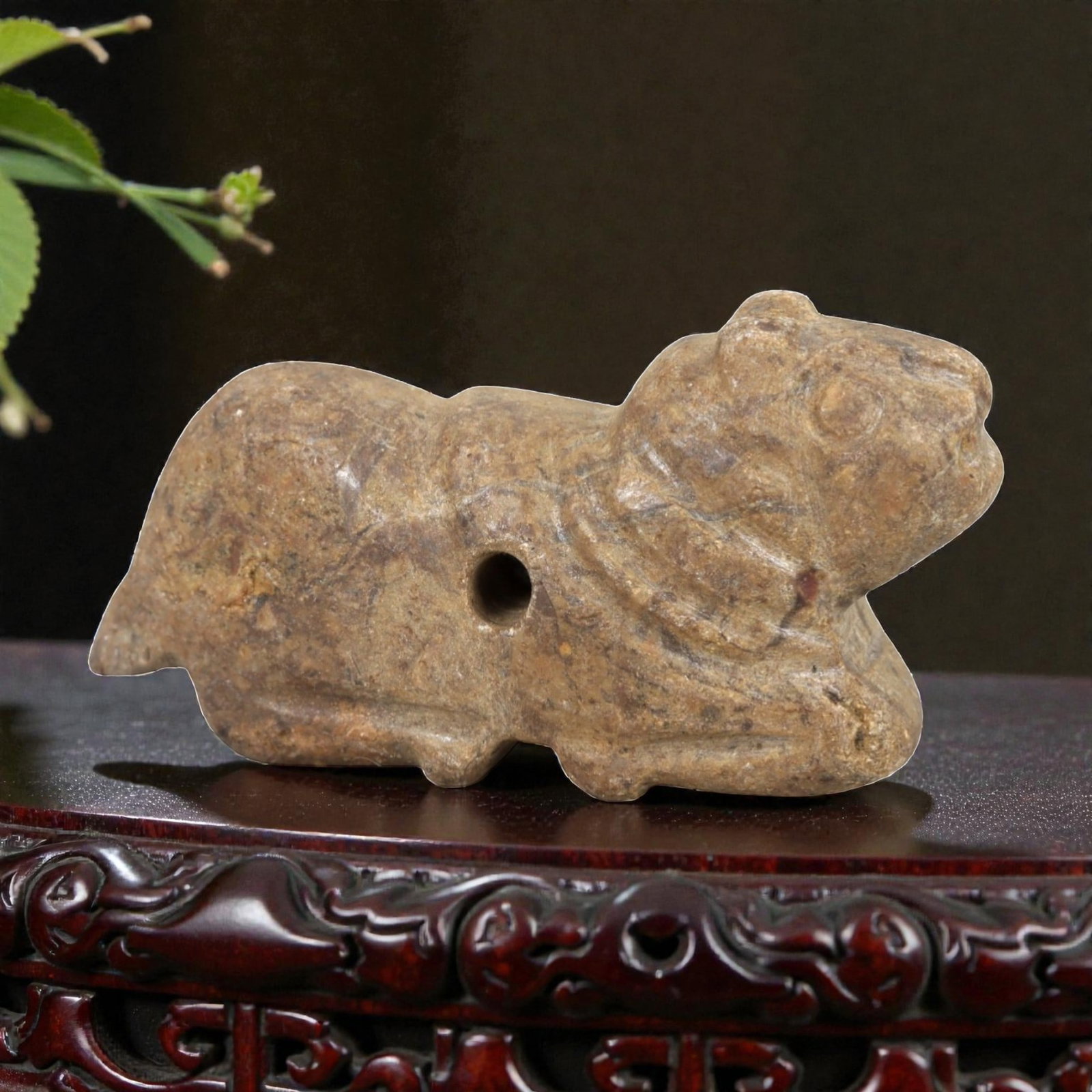 Ancient Stone Zoomorphic Amulet - Near Eastern Animal Figure, 55AM: This amulet is carved from speckled stone, depicting a stylized quadrupedal animal in a crouched, forward-leaning posture, with subtle incised lines defining the neck and facial features. The piece re