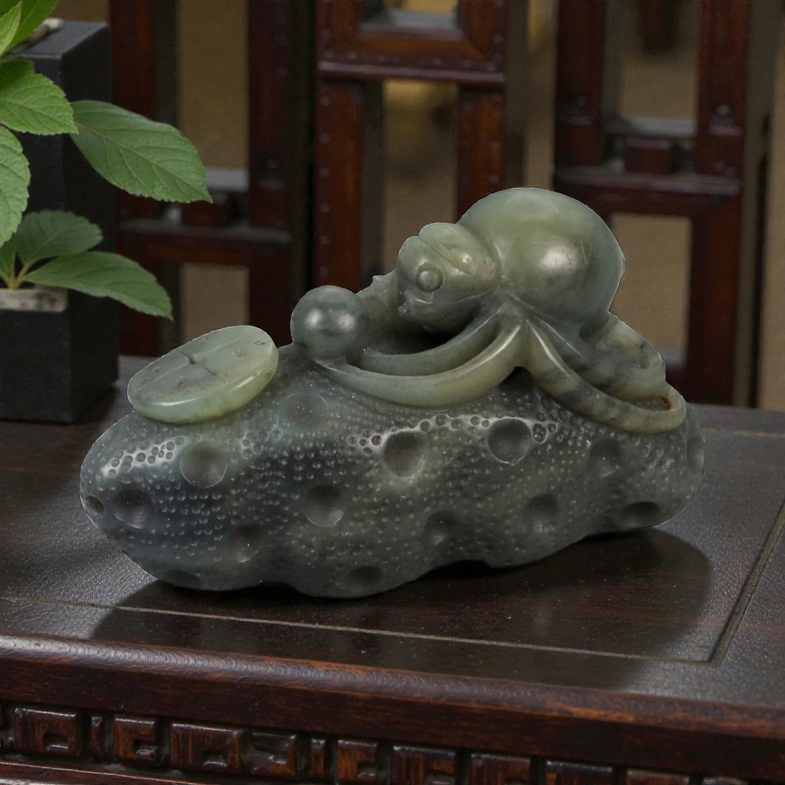 A Chinese Nephrite Jade Spider Carving, 20th Century, 77FB: Carved from dark green nephrite jade with mottled inclusions and areas of lighter translucency, the object is modeled as a spider resting upon a textured ground. The spider is carved in the round, wit