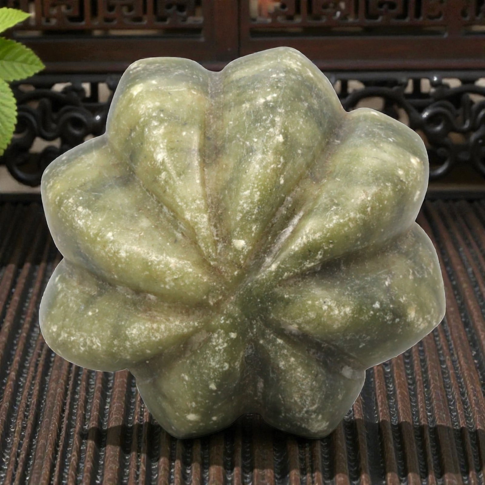 A Chinese Hetian Jade Melon-Shaped Bead, 20th Century, 96FH: Carved from greenish Hetian jade with lighter and darker tonal variations and scattered natural inclusions, the object is modeled in the form of a melon with a rounded, lobed body. The surface is arti