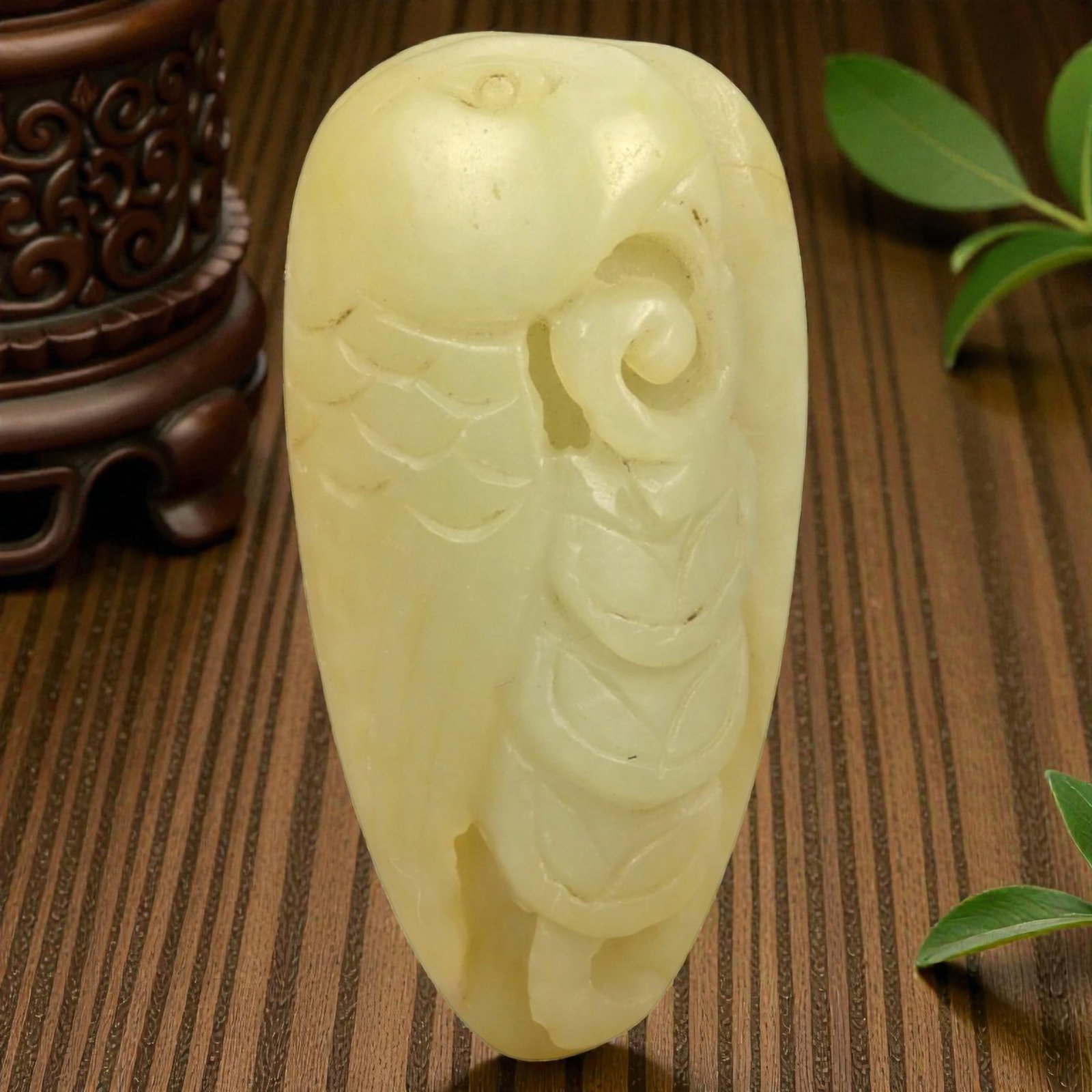 A Chinese Nephrite Jade Fruit Pendant, 58FA: Carved from pale yellow nephrite jade with soft translucency and minor natural inclusions, the pendant is worked in relief to depict a fruiting form, likely a peach or gourd, combined with stylized co
