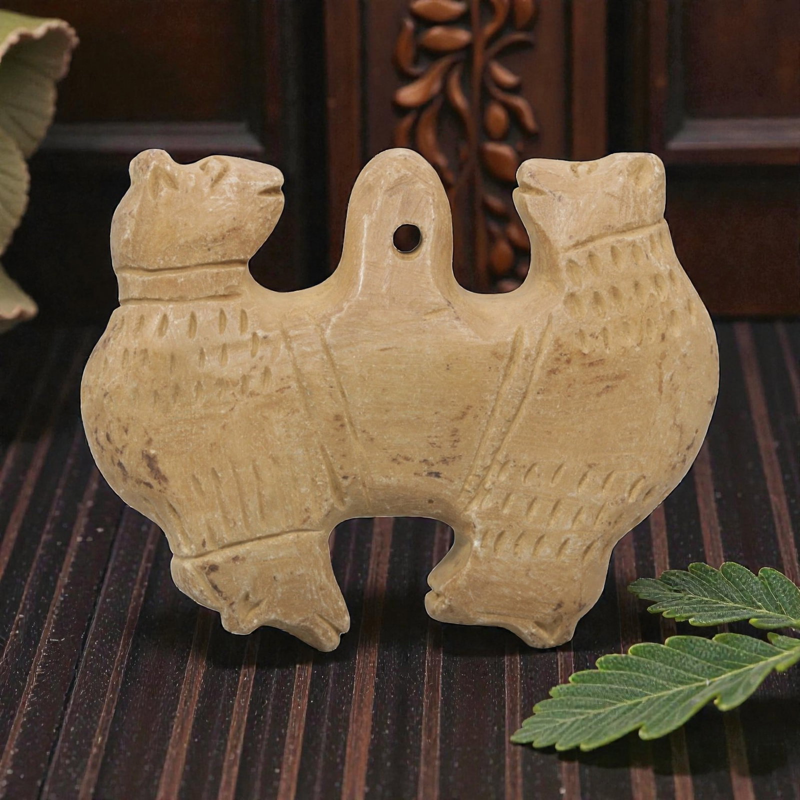Ancient Stone Double Zoomorphic Amulet - Near Eastern, 17WJ: Carved from a fine-grained, pale beige stone, this artifact takes the form of a symmetrical double zoomorphic amulet, depicting two confronting animal figures joined at a central suspension loop. Each