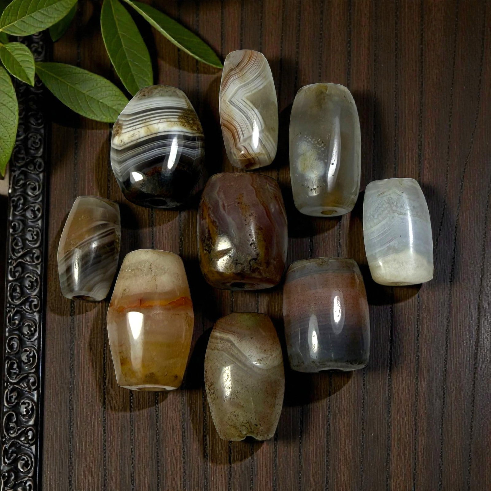 A Lot of 9 Himalayan Banded Agate Beads, Ancient to Antique Period, 51AN: Comprising lot of barrel and ovoid beads, each carved from banded agate with natural tonal variations, many displaying characteristic concentric, linear, and dendritic patterns. The surfaces exhibit s