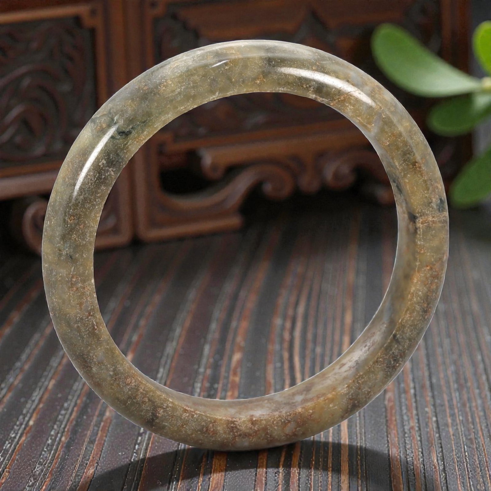 Natural Burmese Type A Jadeite Jade Bangle Bracelet, 20th Century, 77ZK: Carved from jadeite jade with a muted olive-green base and scattered brownish-red inclusions, the bangle is formed as a continuous circular band with a rounded cross-section. The surface is smoothly p