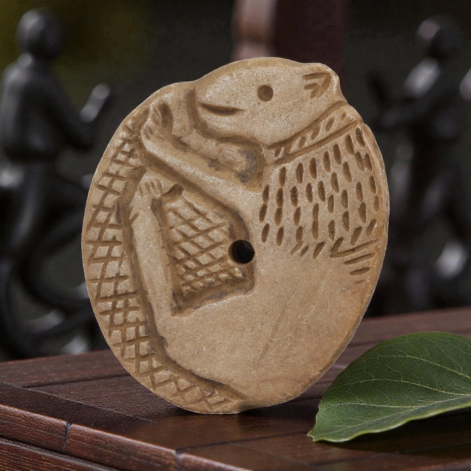 Antique Islamic Steatite Zoomorphic Plaque, 64YD: This antique plaque is carved from light beige steatite, featuring an oval form with a central perforation for suspension. The face displays a stylized zoomorphic motif depicting a creature with an an