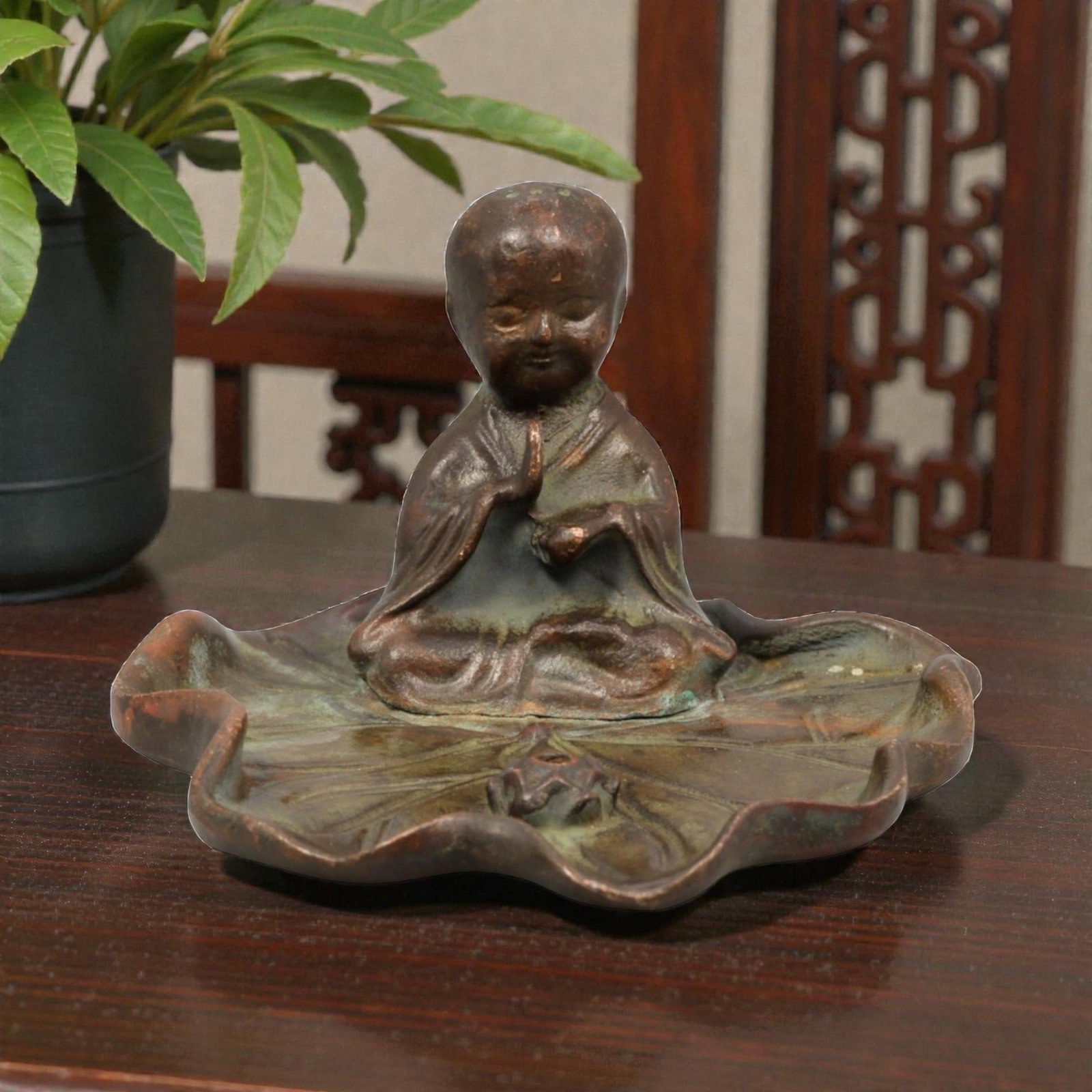 A Chinese Bronze Figure of a Meditating Monk on a Lotus Base, 20th Century, 77YC: Cast in bronze, the figure represents a seated meditating monk shown cross-legged atop a stylized lotus-form base. The figure is modeled with a rounded head, softly defined facial features, and downca