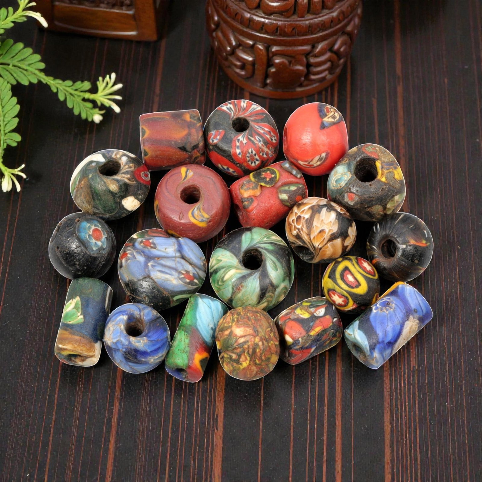 A Lot of 19 Antique/ Vintage Artisan Glass Trade Beads, 27WM: A diverse collection of 19 glass trade beads, varying in form from spherical, barrel, and cylindrical to faceted shapes, all with central perforations for threading. The beads feature intricate mosaic