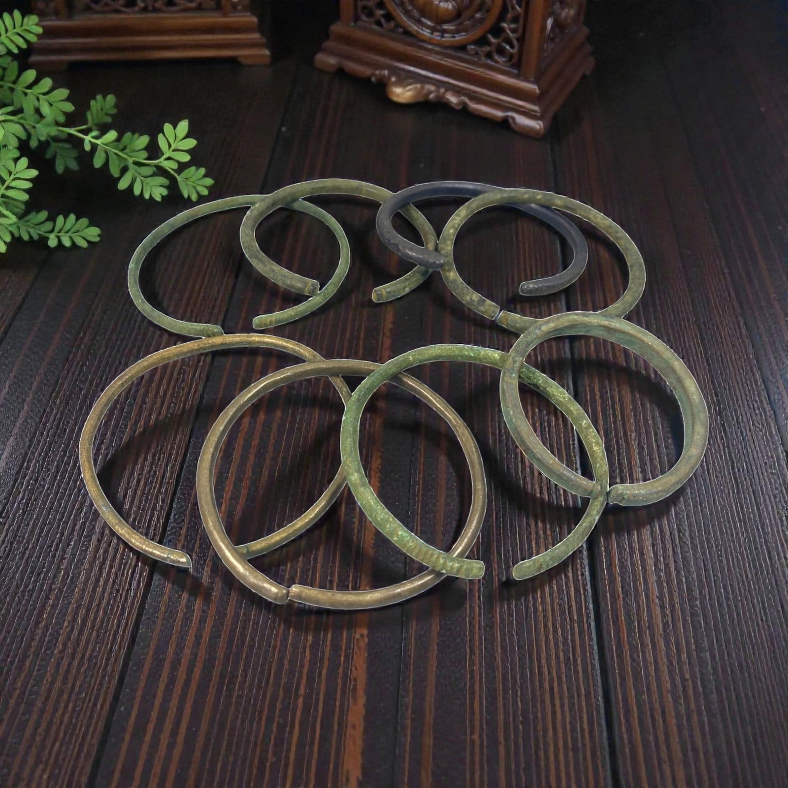Lot of 8 Roman Bronze Bracelets, Circa 1st-4th Century CE, 94AC: Each bracelet is formed from a single length of bronze, hammered into a circular band with open, overlapping terminals. The metal exhibits varied patination, including green, brown, and dark surfaces,
