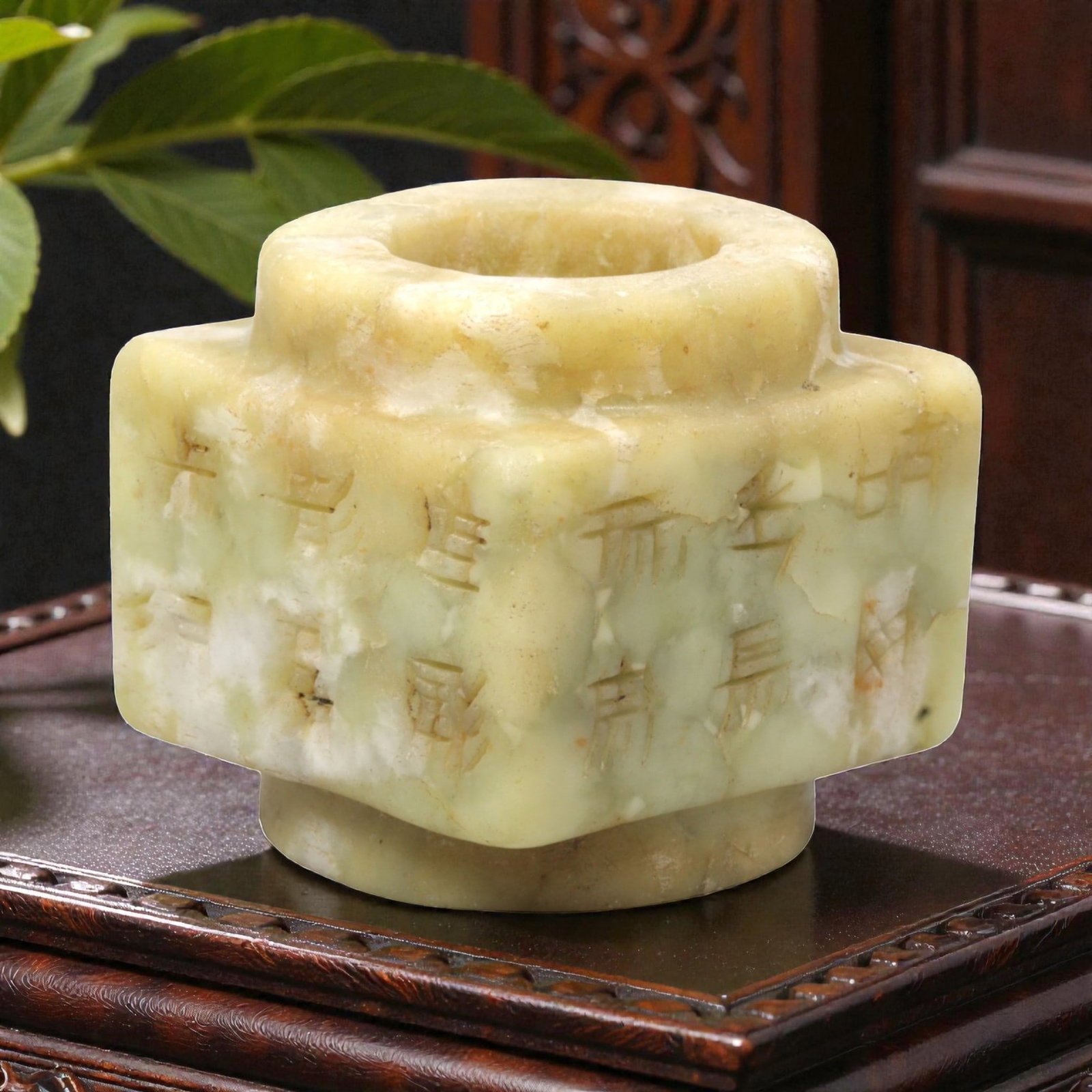 A Chinese Hetian Jade Cylindrical Ornament with Incised Characters, 20th Century, 93FH: Carved from mottled pale green and creamy-yellow Hetian jade, the object is formed as a stepped cylindrical vessel-like ornament with a thick-walled circular aperture and projecting shoulder. The exte