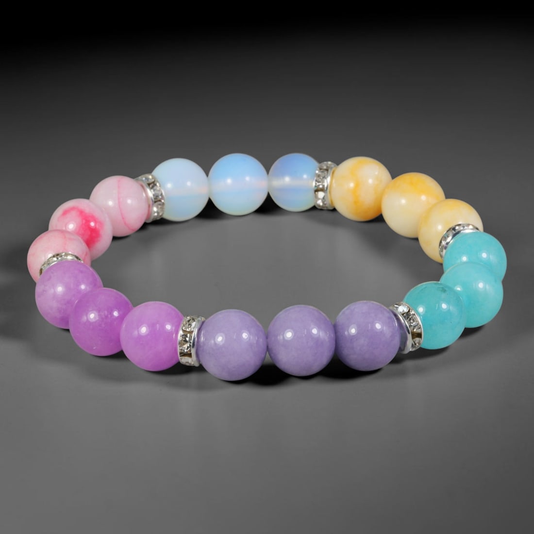 Natural Mixed Stone Beaded Bracelet - Polished Round Bead Strand, 36YM: This elastic stretch bracelet features uniformly spherical polished natural mineral beads separated by silvered metal spacers set with clear crystalline details. The hard stone shows soft lavender, pi