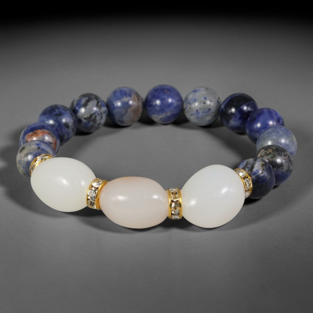 Natural Sodalite & White Jade Beaded Bracelet - Mixed Shape Bead Strand, 55FA: This elastic stretch bracelet pairs 10mm spherical sodalite beads with barrel-shaped polished white jade beads, divided by gold-toned metal spacers inlaid with clear crystalline details. The sodalite 