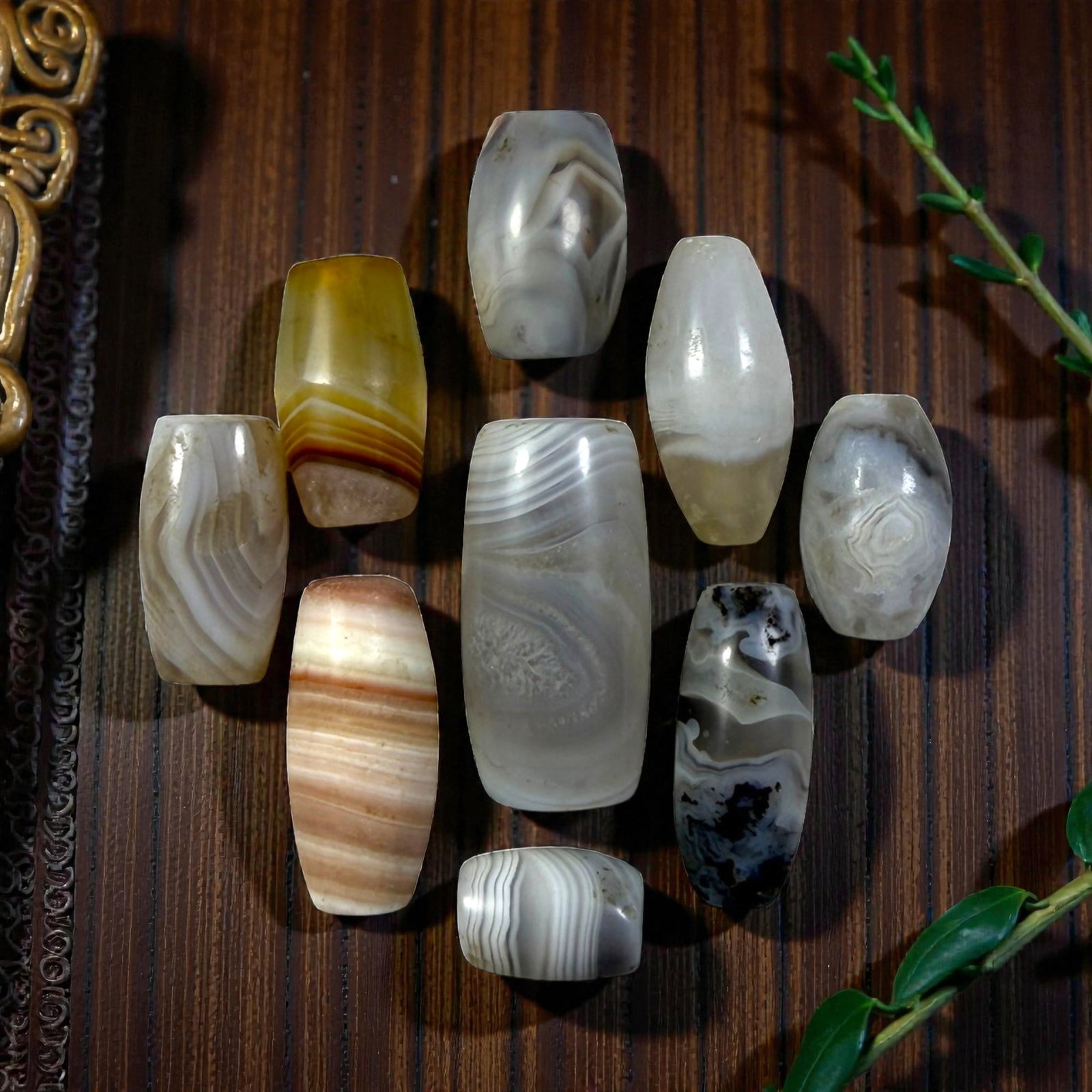 A Lot of 9 Himalayan Banded Agate Beads, Ancient to Antique Period, 33YD: Comprising lot of barrel and ovoid beads, each carved from banded agate with natural tonal variations, many displaying characteristic concentric, linear, and dendritic patterns. The surfaces exhibit s