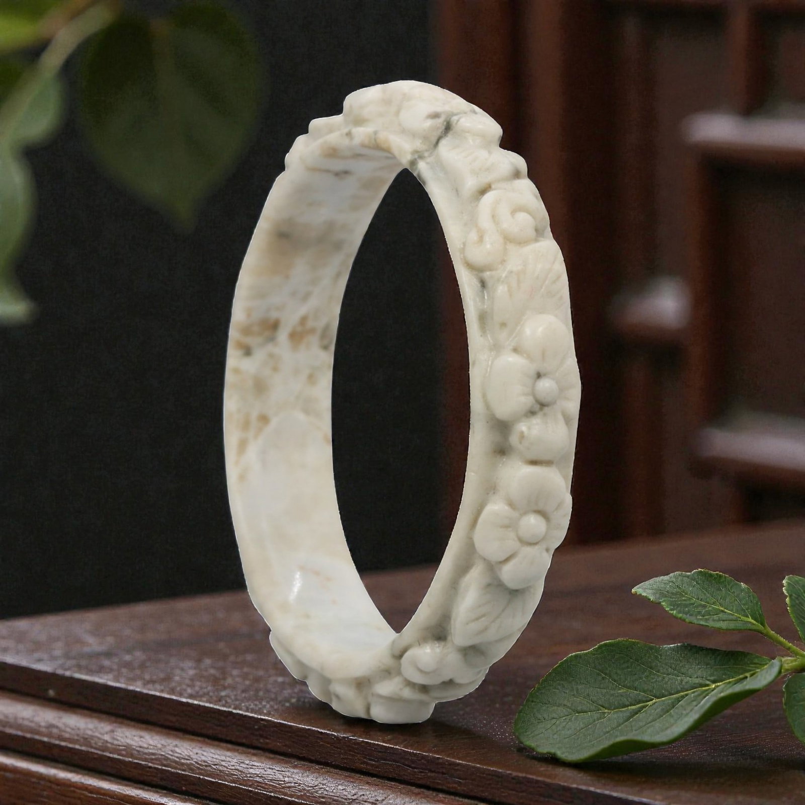 Natural Burmese Type A Carved Jadeite Jade Bangle Bracelet, 20th Century, 75ZL: A fine jadeite bangle of flattened circular form, masterfully carved in relief with a continuous band of floral blossoms and scrolling foliate motifs. The stone exhibits a creamy white base, heavily a