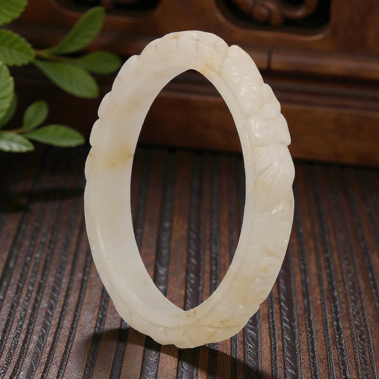 Natural Burmese Type A Carved Jadeite Jade Bangle Bracelet, 20th Century, 44ZL: A fine jadeite bangle of flattened circular form, masterfully carved in relief with a continuous band of floral blossoms and scrolling foliate motifs. The stone exhibits a creamy white base, accented 