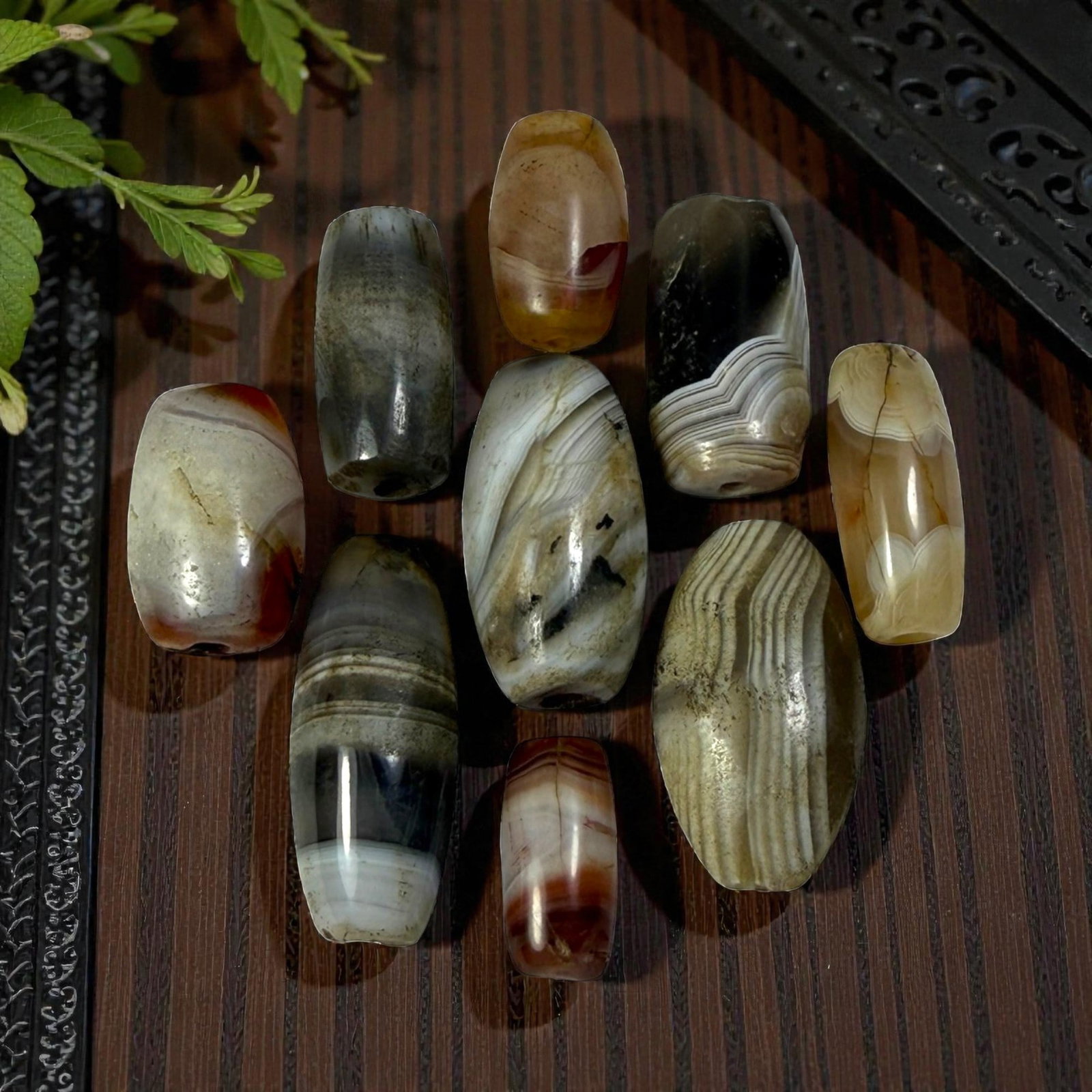 A Lot of 9 Himalayan Banded Agate Beads, Ancient to Antique Period, 49AN: Comprising lot of barrel and ovoid beads, each carved from banded agate with natural tonal variations, many displaying characteristic concentric, linear, and dendritic patterns. The surfaces exhibit s
