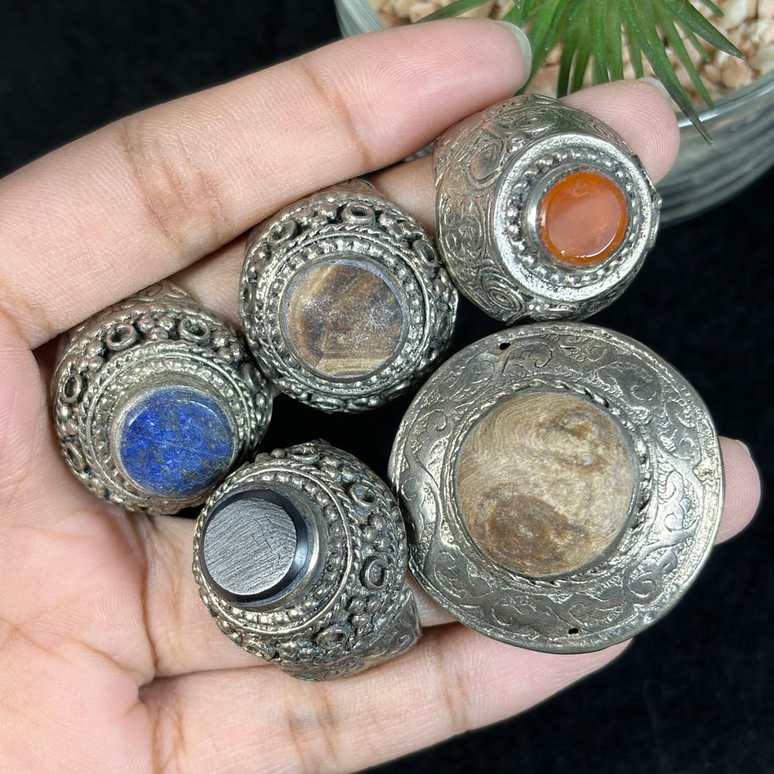 Vintage Tibetan Carved Silvered Stone Inlay Rings Lot, 20AS: This set includes five untested silvered alloy adjustable rings crafted in traditional Tibetan tribal style, each featuring elaborate hand-stamped scroll and granulation filigree detailing across the 