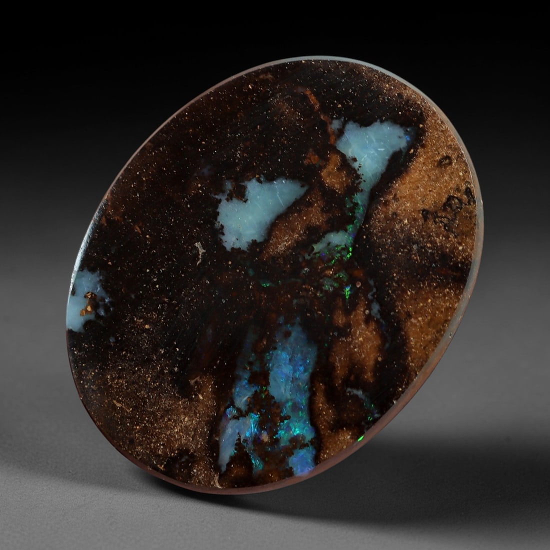 5.01 Carats Koroit Boulder Opal Cabochon - Natural Australian Stones 12.2x9.6mm, 8XM: This exceptional 5.01-carat Koroit boulder opal cabochon is a natural geological masterpiece, featuring striking patches of milky blue opal infused with vivid iridescent play-of-color, set against a r